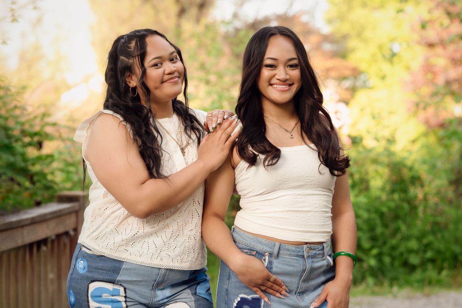 Two people in coordinating denim and white outfits laugh together during an outdoor photo session in golden sunlight.