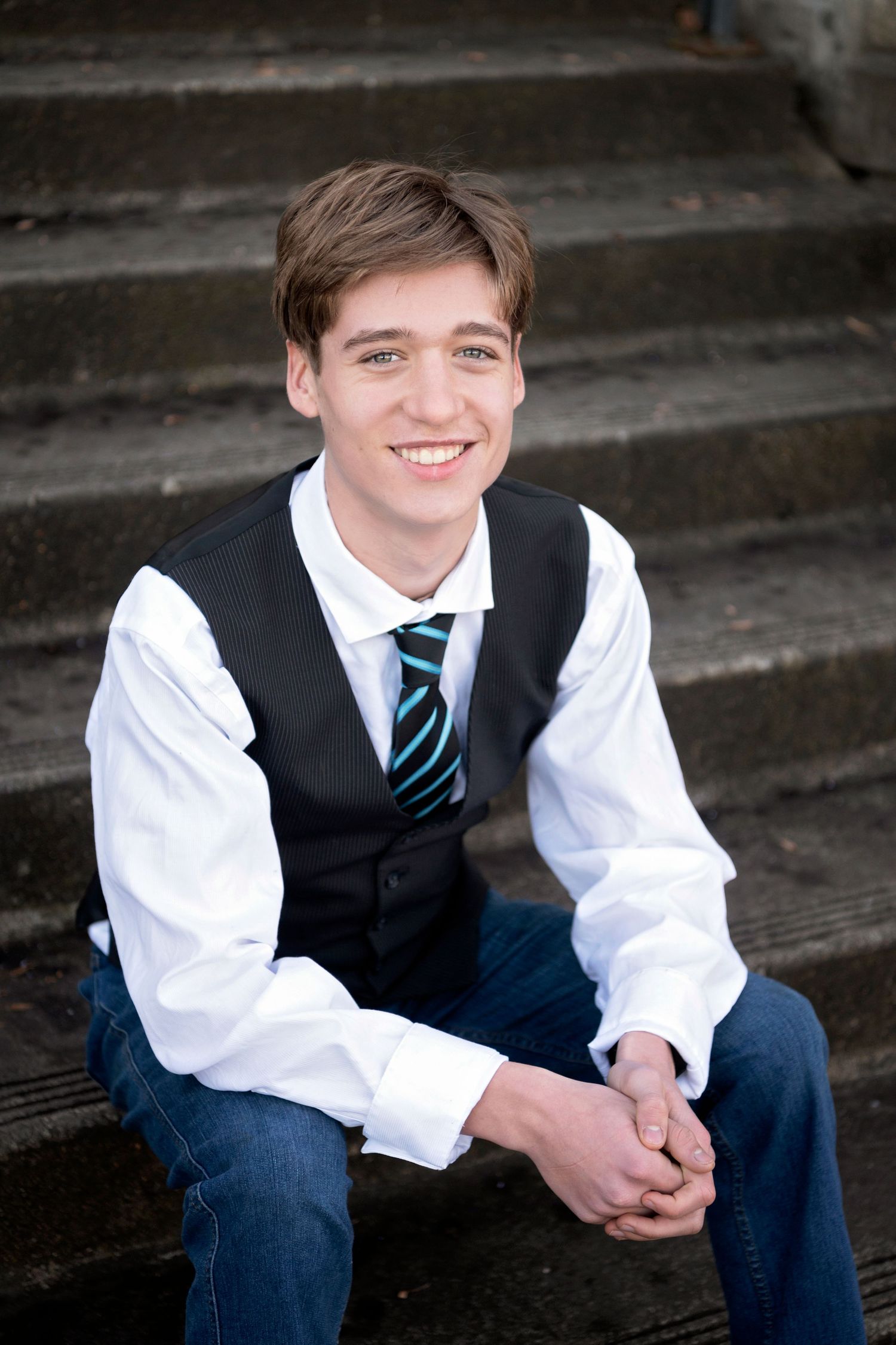 A series of formal portraits showing someone in a navy vest, white shirt and striped tie sitting on wooden steps.
