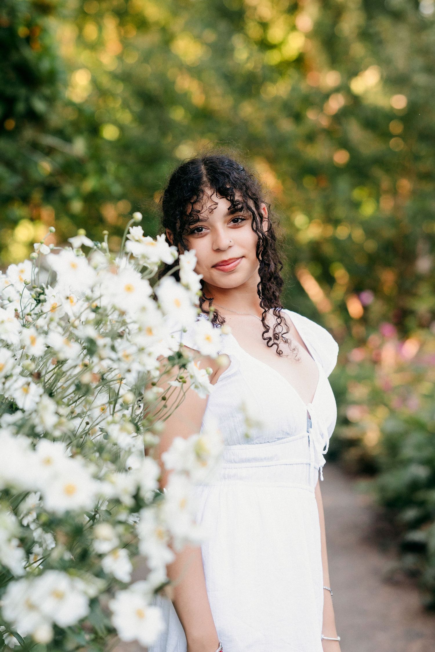 A series of outdoor portrait photographs featuring a person in white clothing surrounded by delicate white flowers and greenery.
