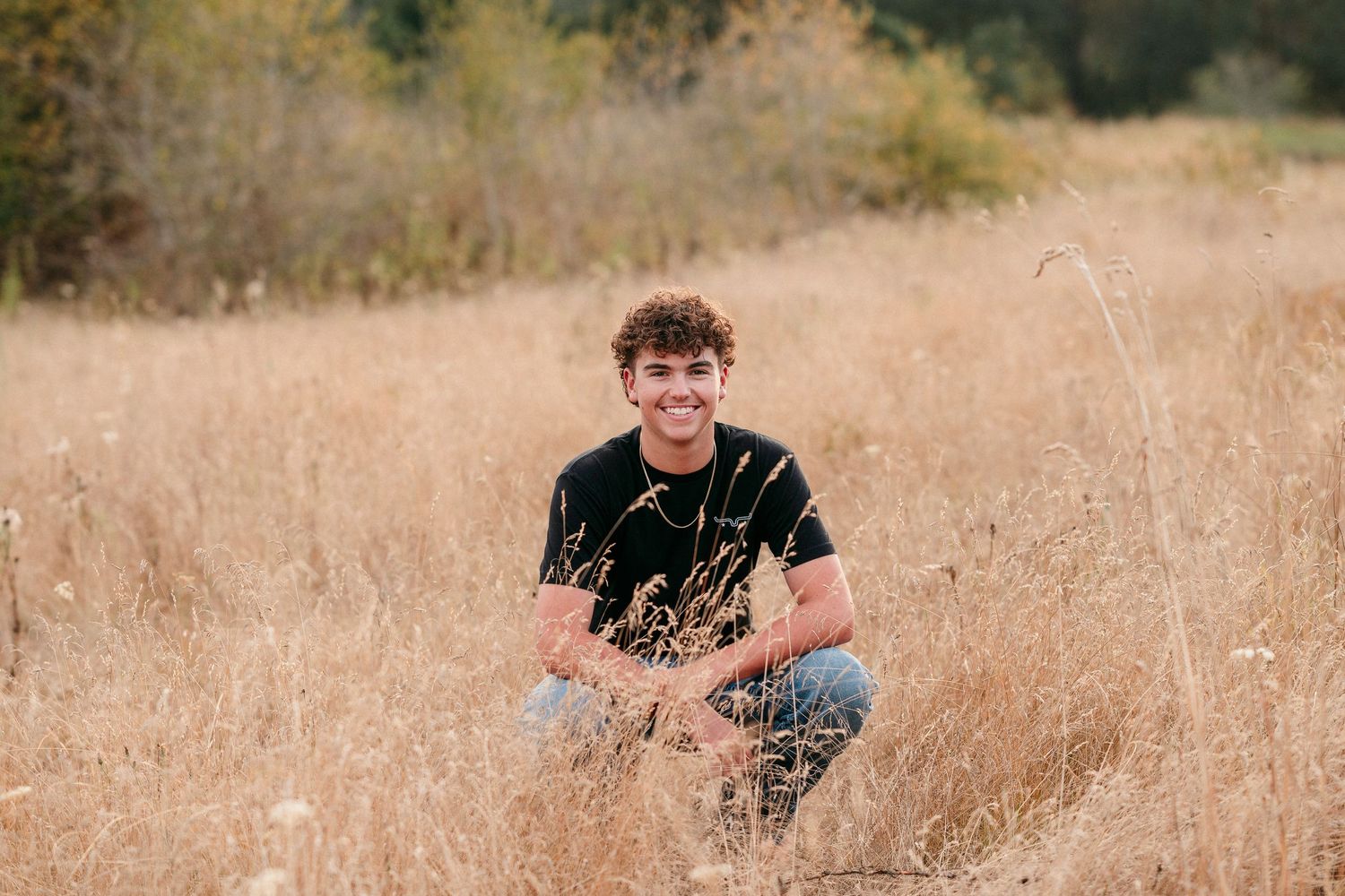 Natural outdoor photography session in a sunlit meadow with dried grass.