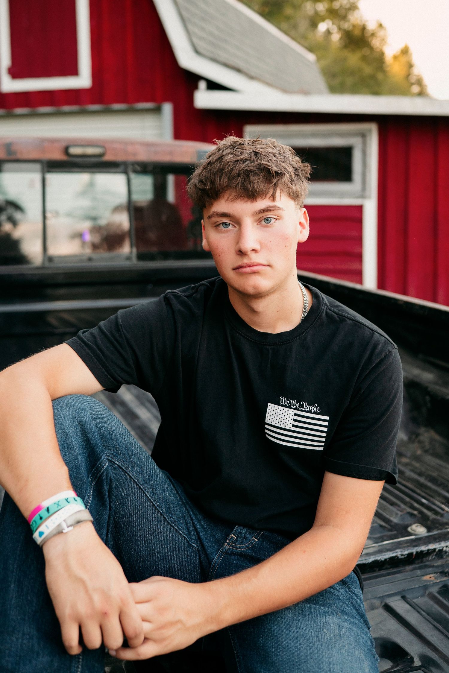 Casual portrait series of someone sitting in a pickup truck bed wearing a black t-shirt with an American flag patch.