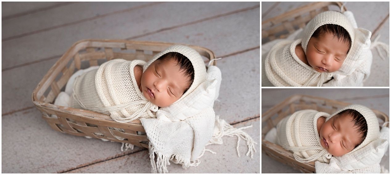A sleeping newborn baby wrapped in white fabric rests peacefully in a woven basket.