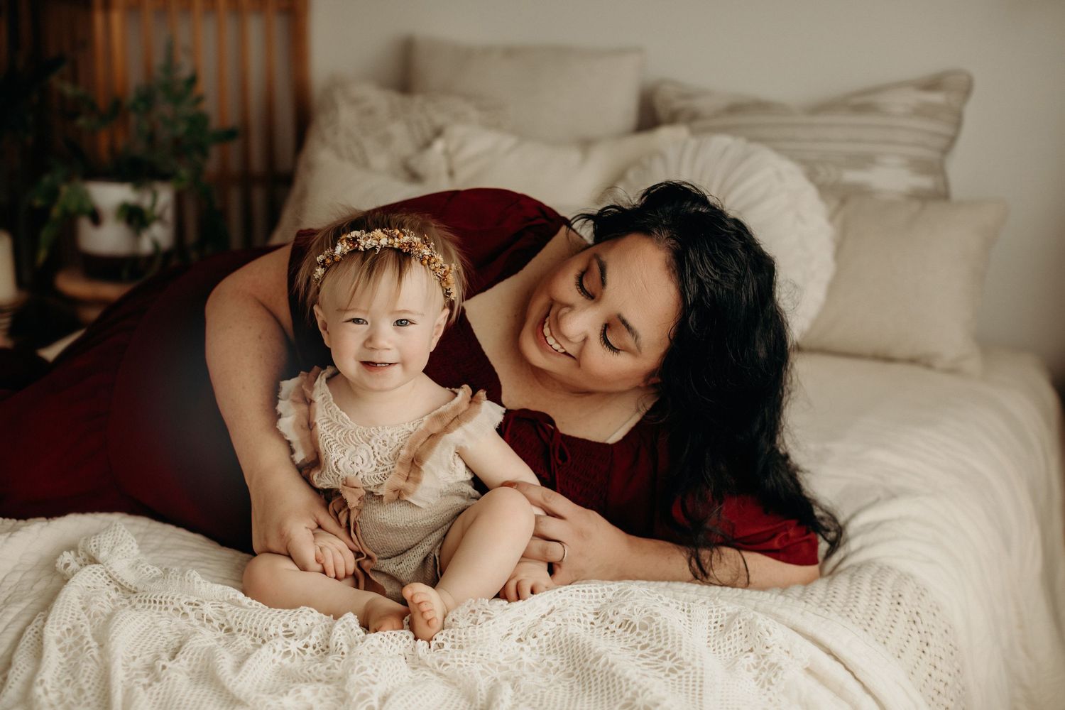 A heartwarming scene of parental bonding with a small child on a cozy white bed decorated with soft blankets.