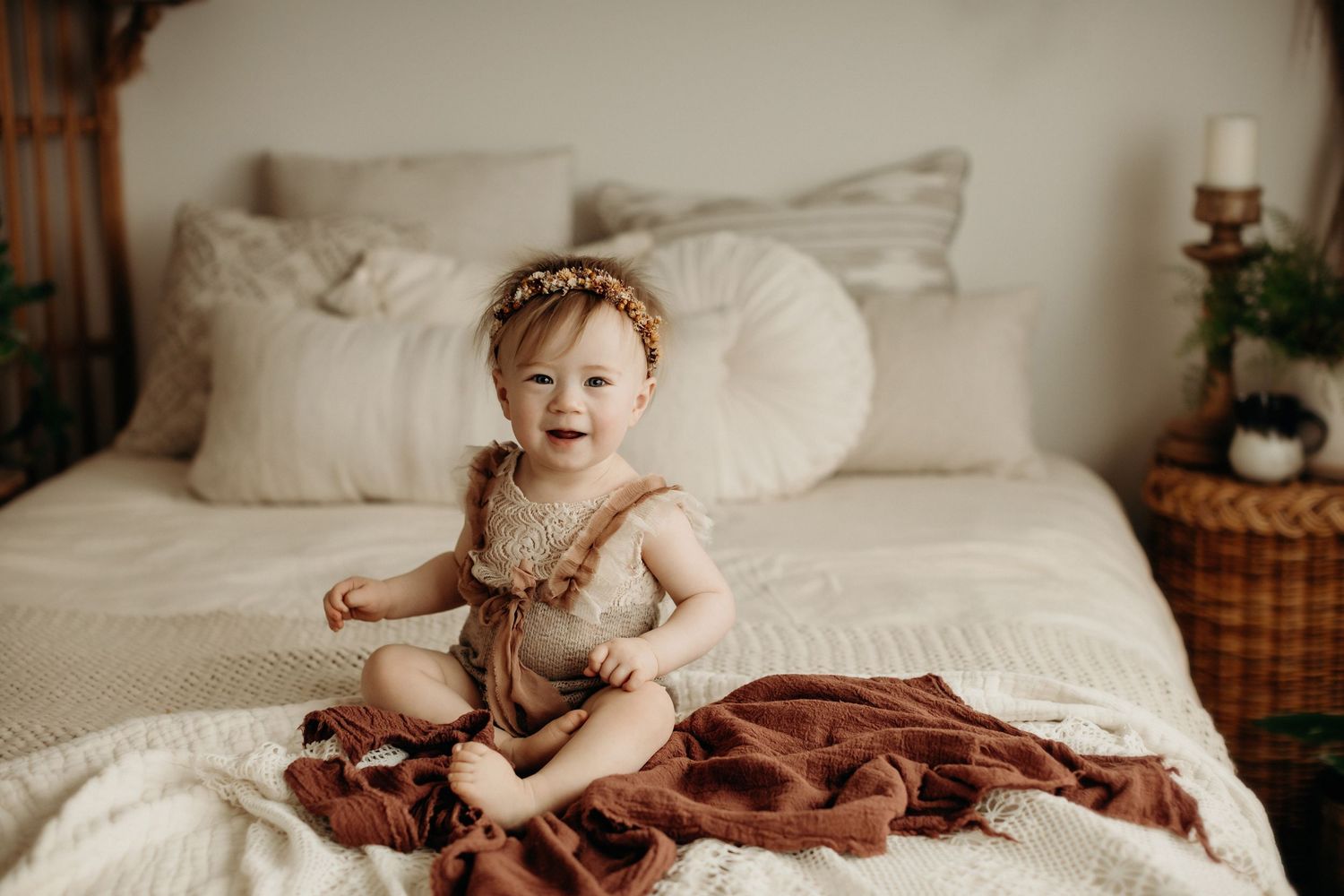 A series of warm toned lifestyle photos showing a baby sitting on a white bed with brown textured blankets and decorative elements.