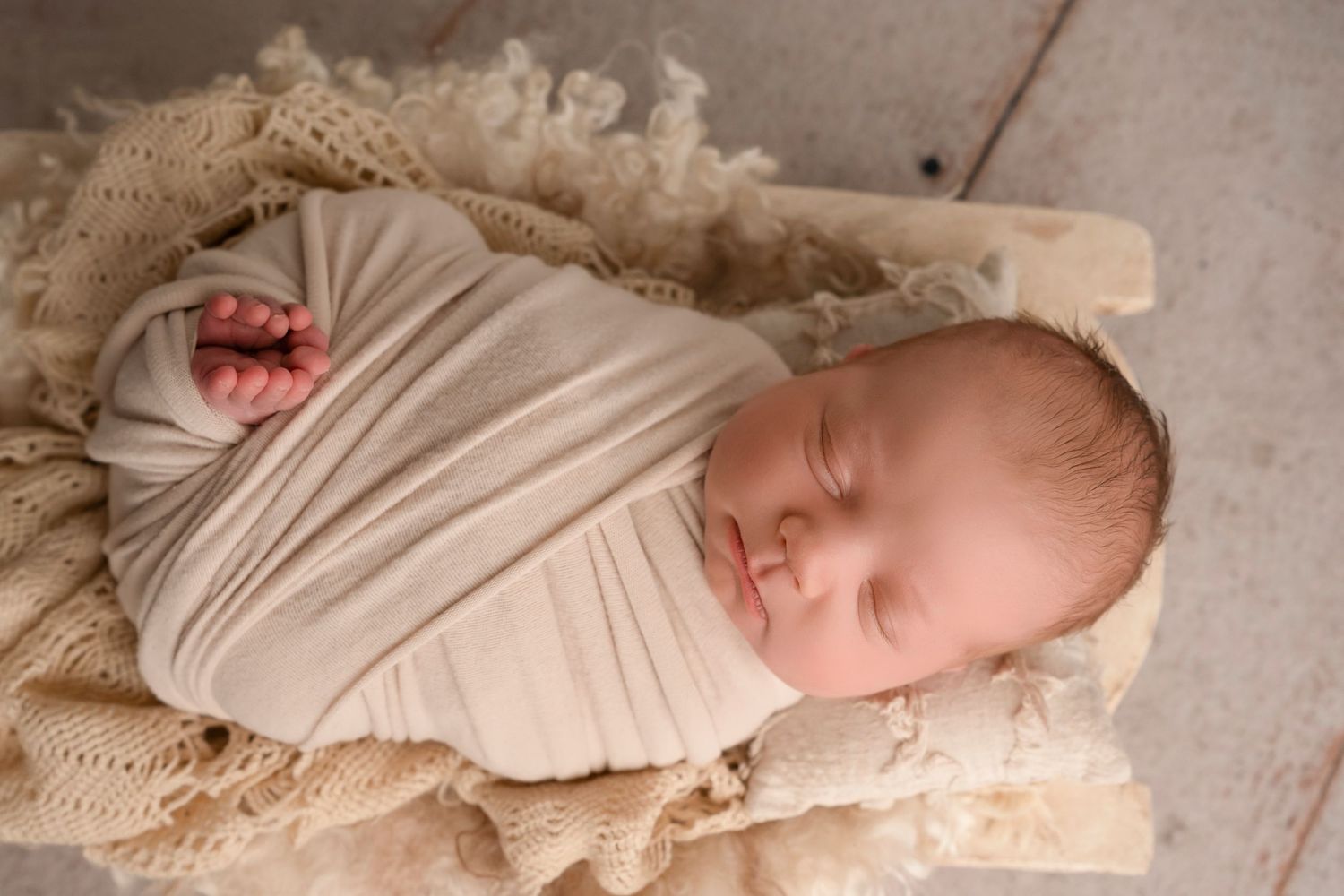 Collage of newborn photography showing six different poses on cream colored blankets and wraps.