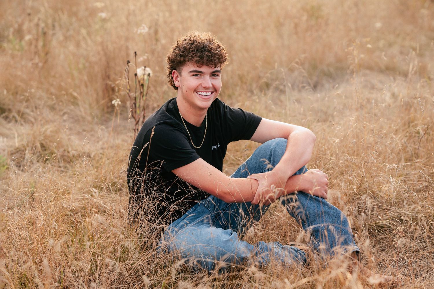 A series of casual outdoor portrait photos in a golden field shows someone in a black shirt and jeans relaxing in nature.