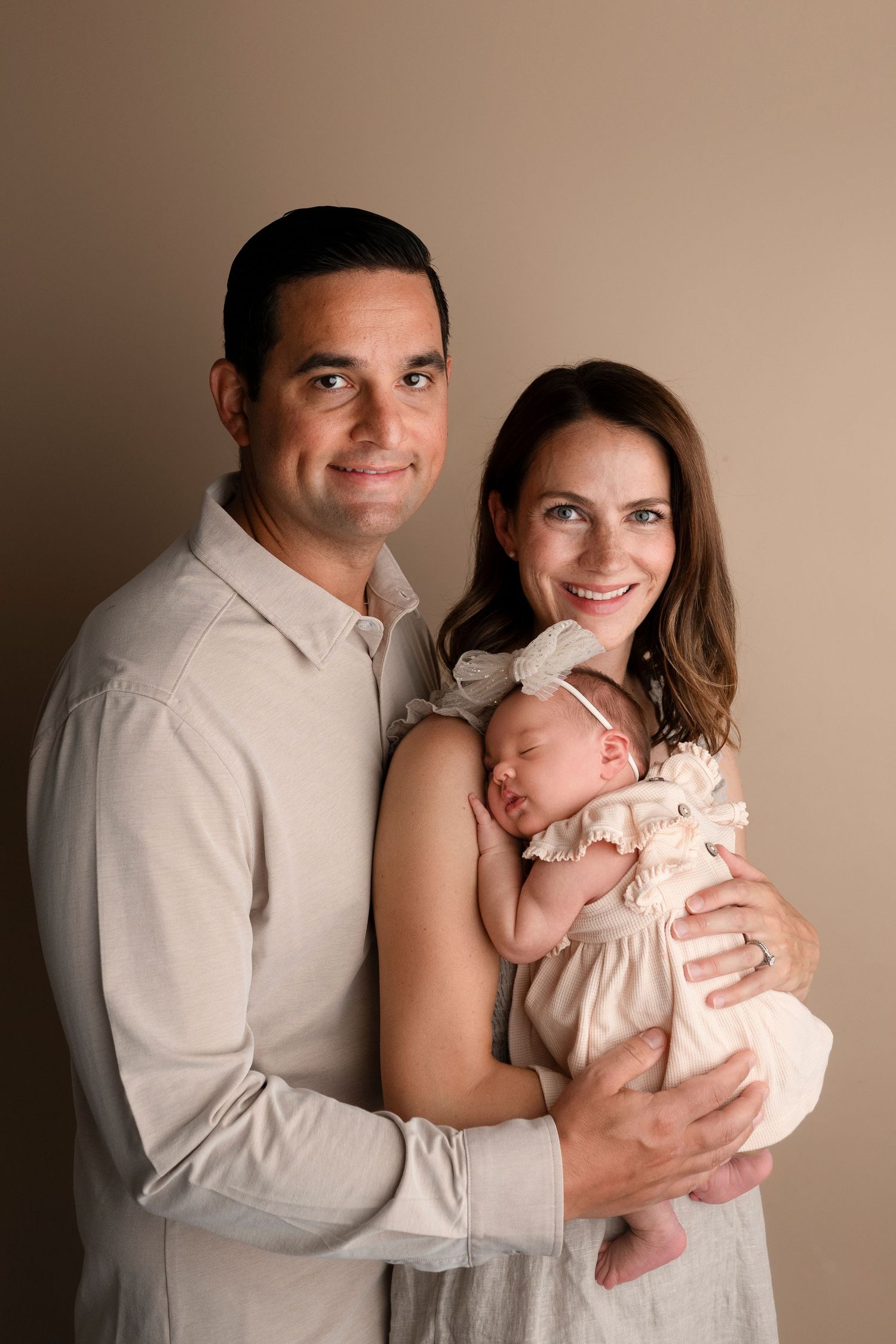 A sweet family portrait series showing tender moments between parents and their baby in soft, neutral tones.