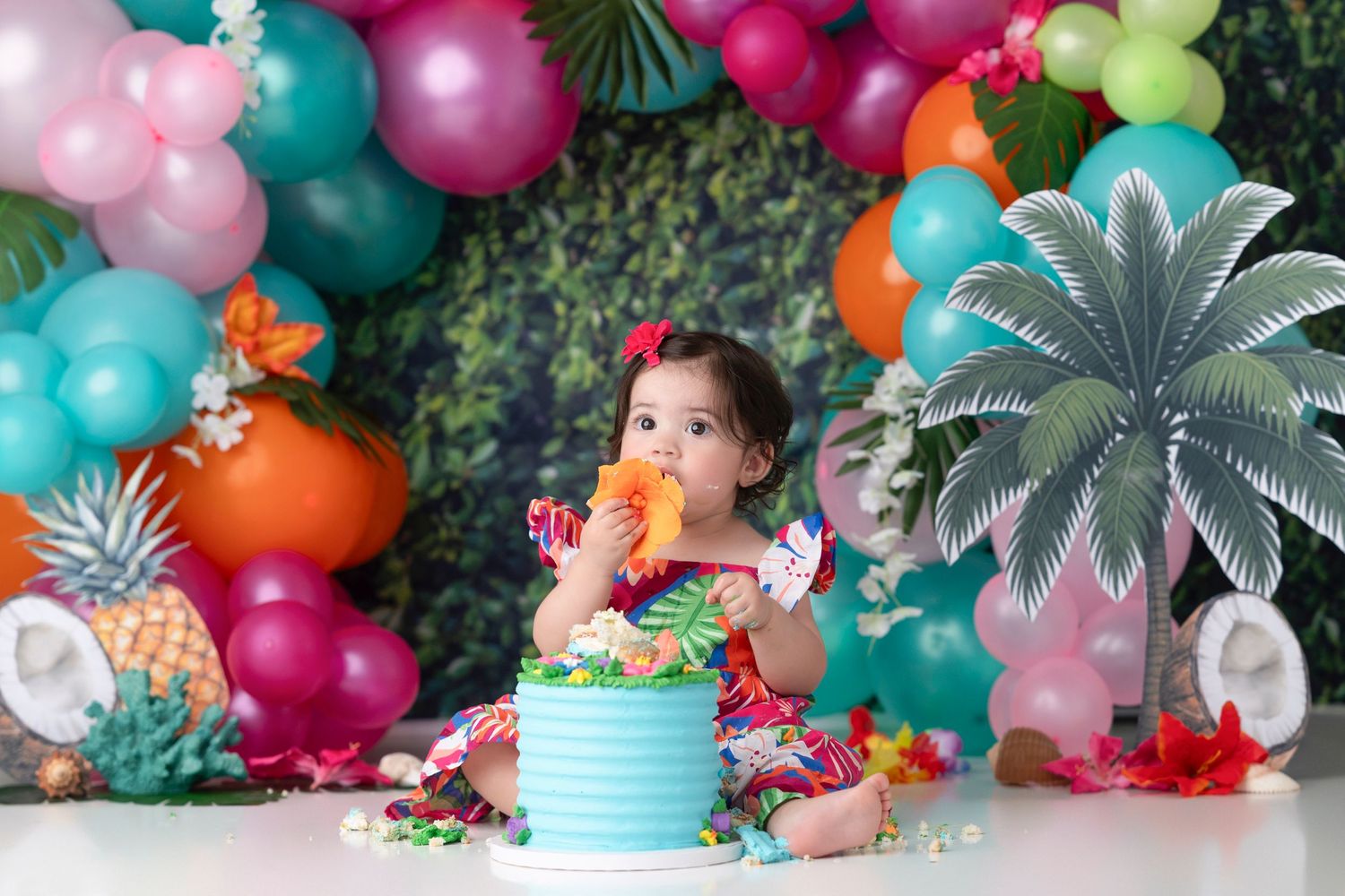 Tropical party decorations featuring colorful balloons, palm leaves, and pineapple accents create a festive luau atmosphere.