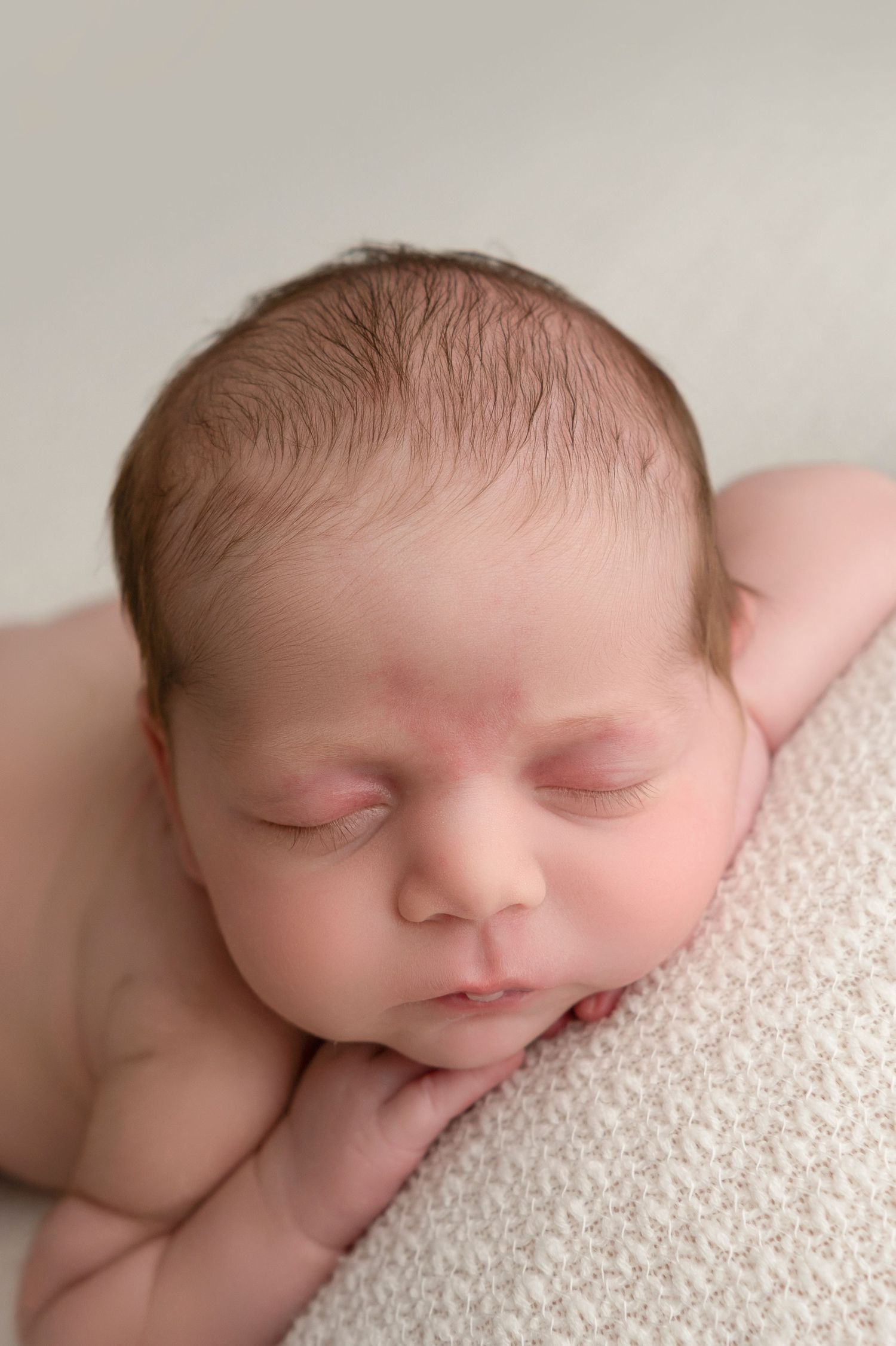 A series of four peaceful newborn baby photos showing gentle sleeping poses on soft white textured fabric.