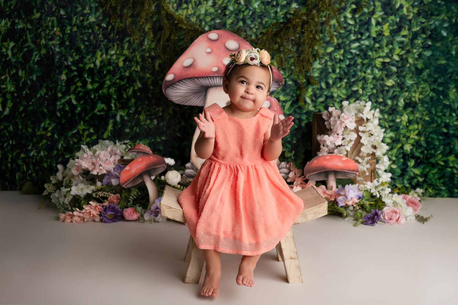 Adorable portrait session featuring coral dress and floral backdrop with decorative elements.