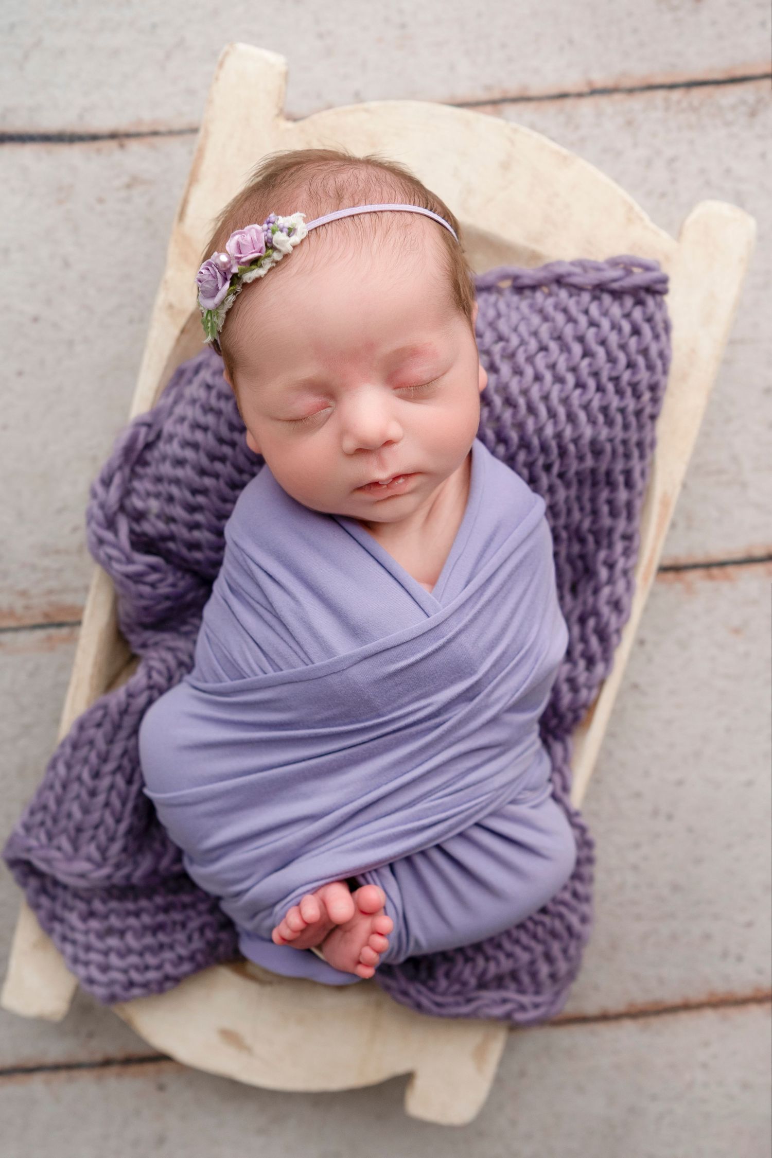 Newborn baby wrapped in soft purple fabric lying on textured purple blanket in collage of four similar poses.