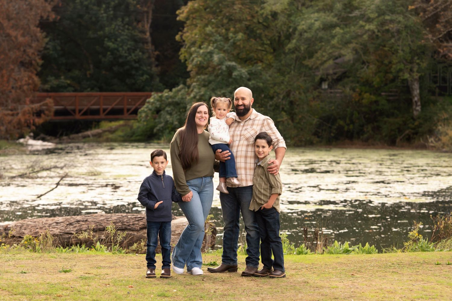 A group of people in casual attire pose together outdoors in a scenic natural setting during autumn.