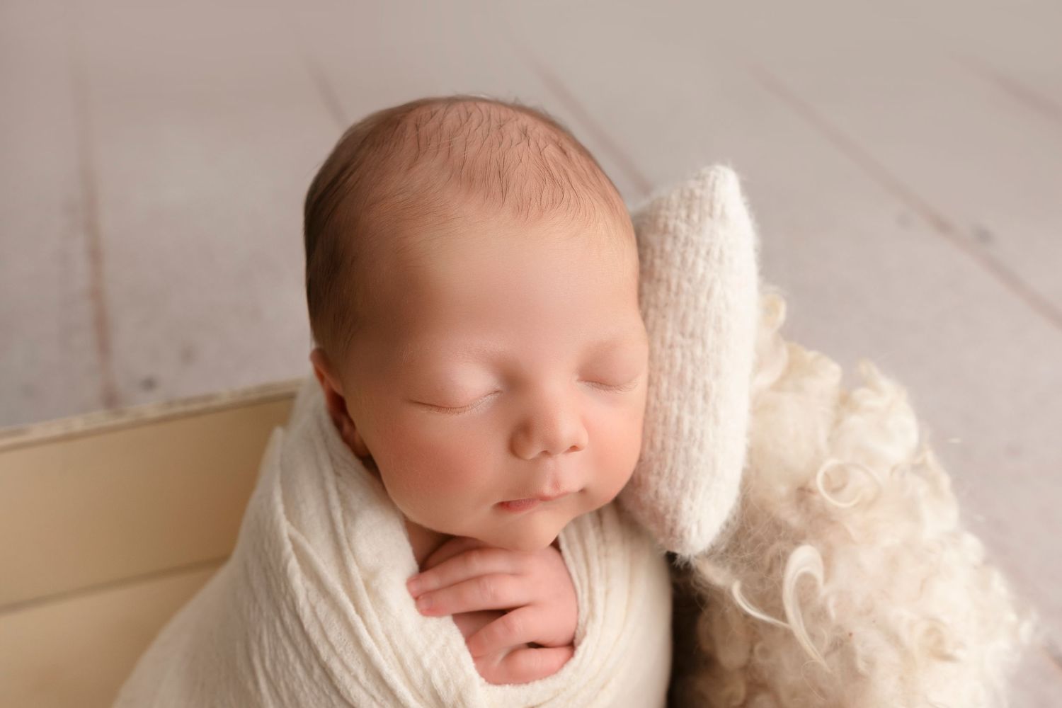 A series of newborn baby portraits in soft, neutral tones showing peaceful sleeping poses on white textiles.
