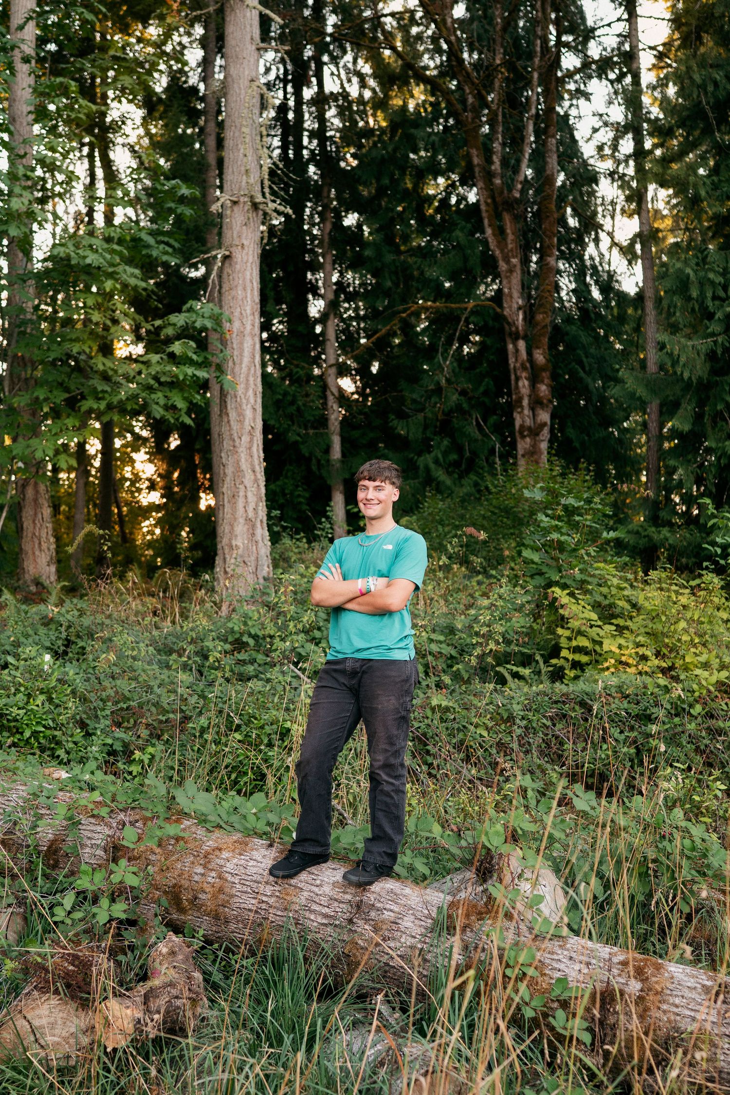 A series of outdoor portraits in a wooded area with tall evergreen trees and fallen logs at sunset.