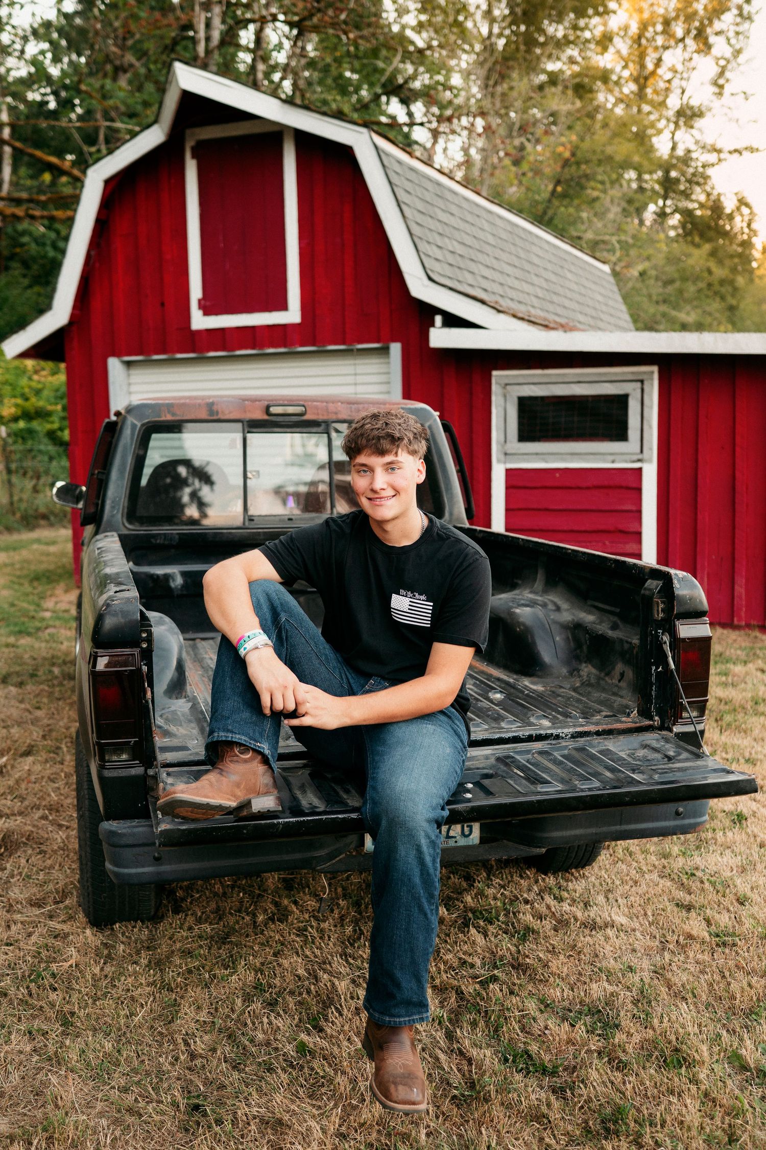 Multiple shots of someone relaxing in the back of a black pickup truck with a red barn in the background.