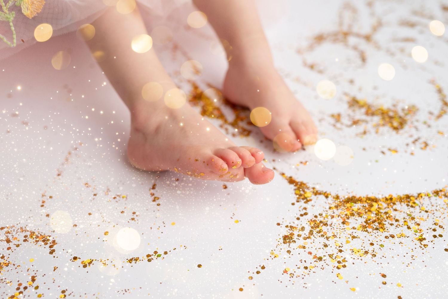 Sprinkling gold glitter or sprinkles onto a white surface with hands in a creative pattern.
