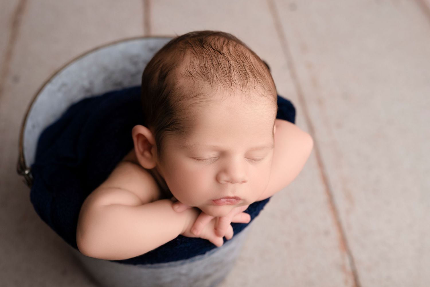 Newborn peacefully resting in cozy navy and cream setup with natural lighting.