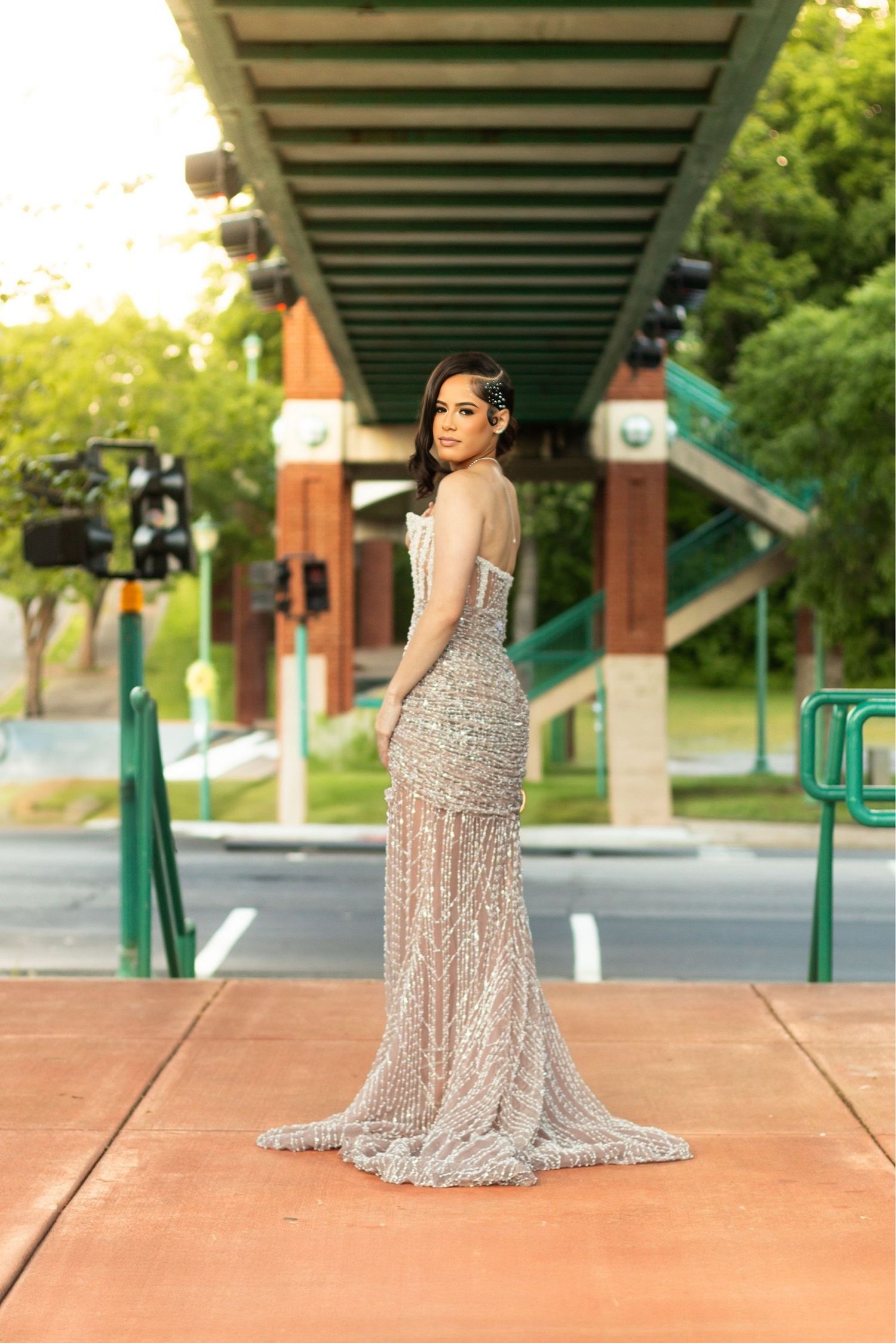 Elegant formal photo of someone in a sparkly full-length gown under an outdoor pergola.