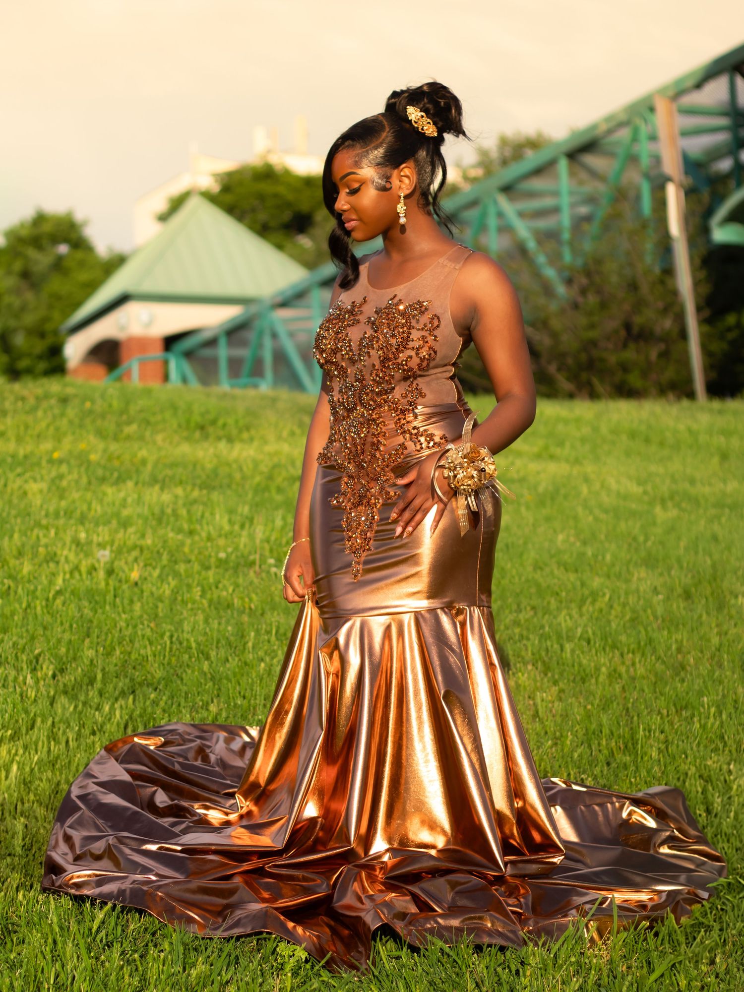 A stunning copper-colored mermaid gown with intricate details photographed on a grassy lawn at golden hour.