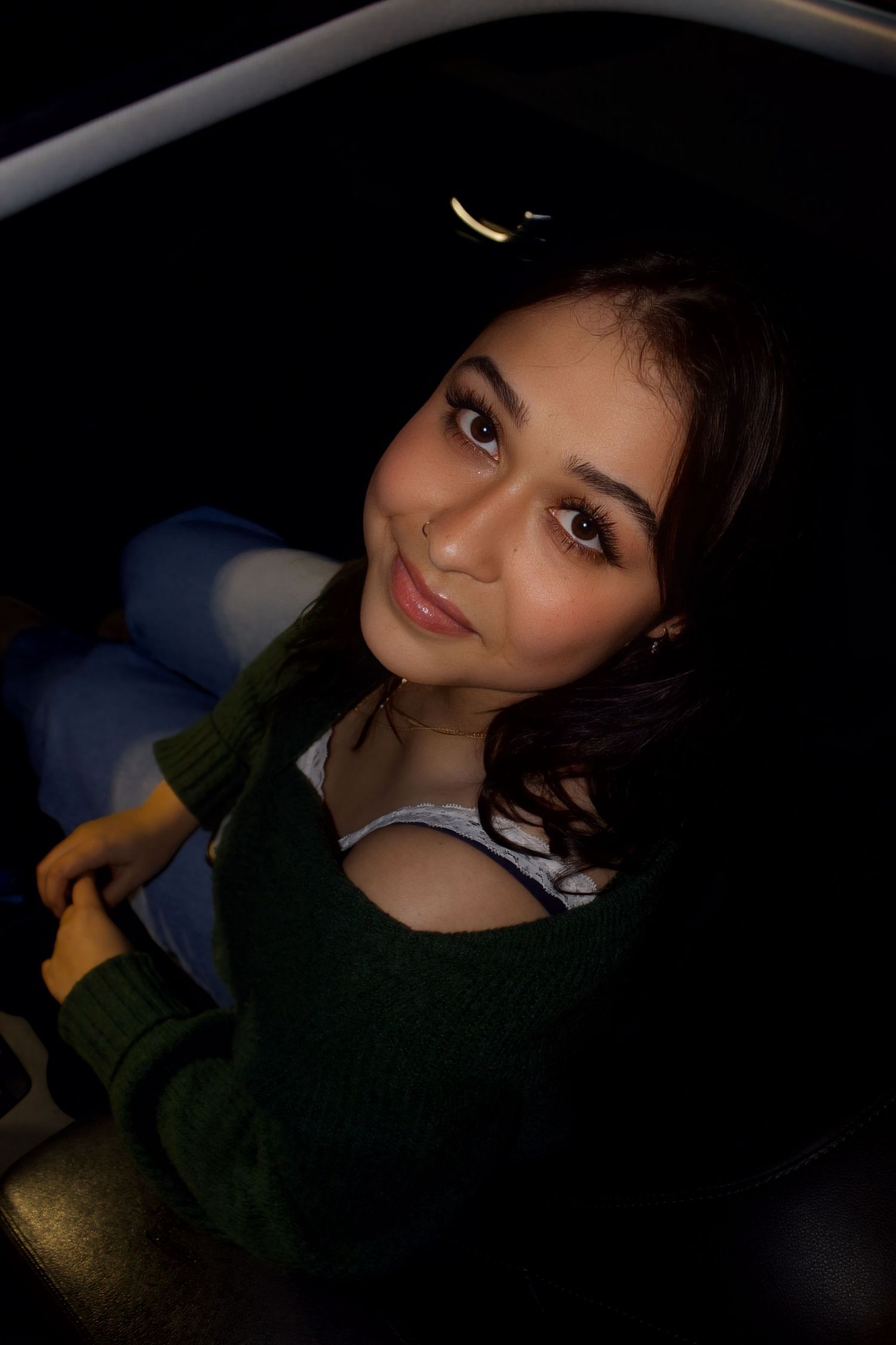 A nighttime portrait in a car featuring a dark green sweater and soft lighting.
