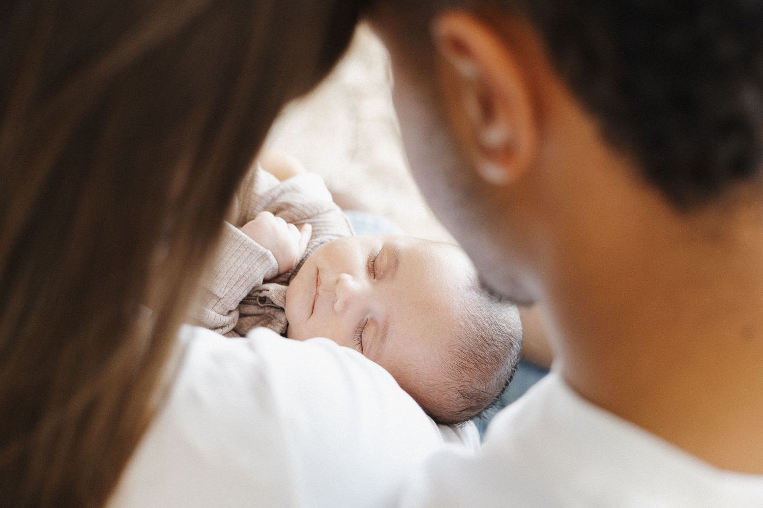 Two parents gaze at their sleeping newborn in Belconnen Canberra photography studio