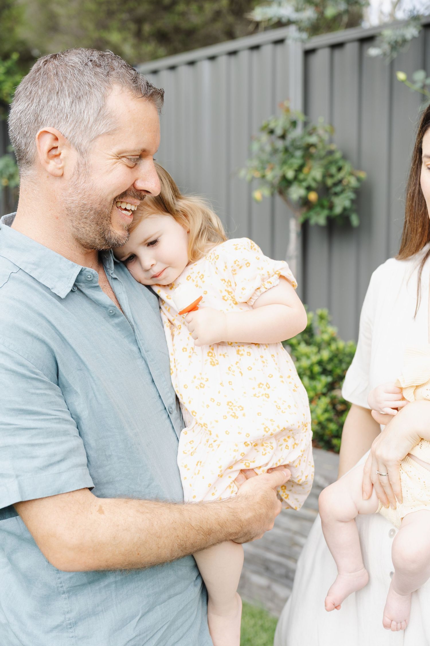 Toddler snuggles dad in their Canberra backyard during a photoshoot