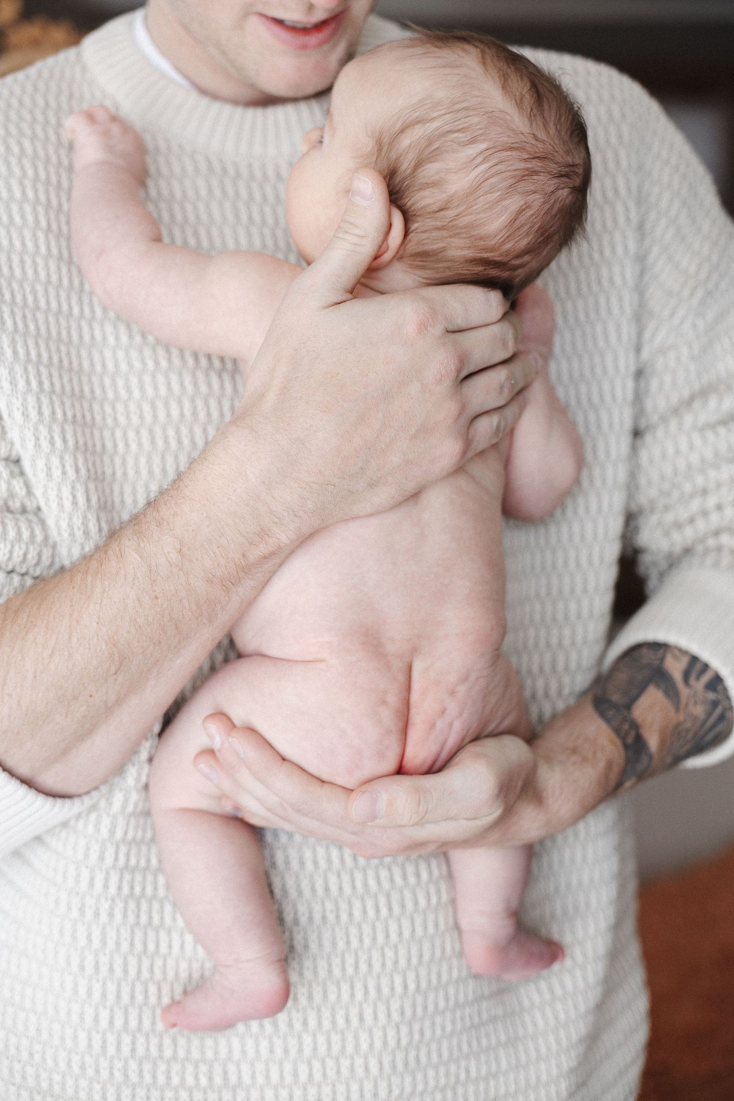 Naked newborn baby cuddled by dad in Belconnen Canberra photography studio