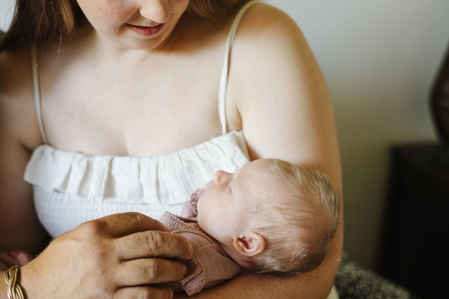 A new mother looks down at her sleeping newborn baby in a Canberra photoshoot