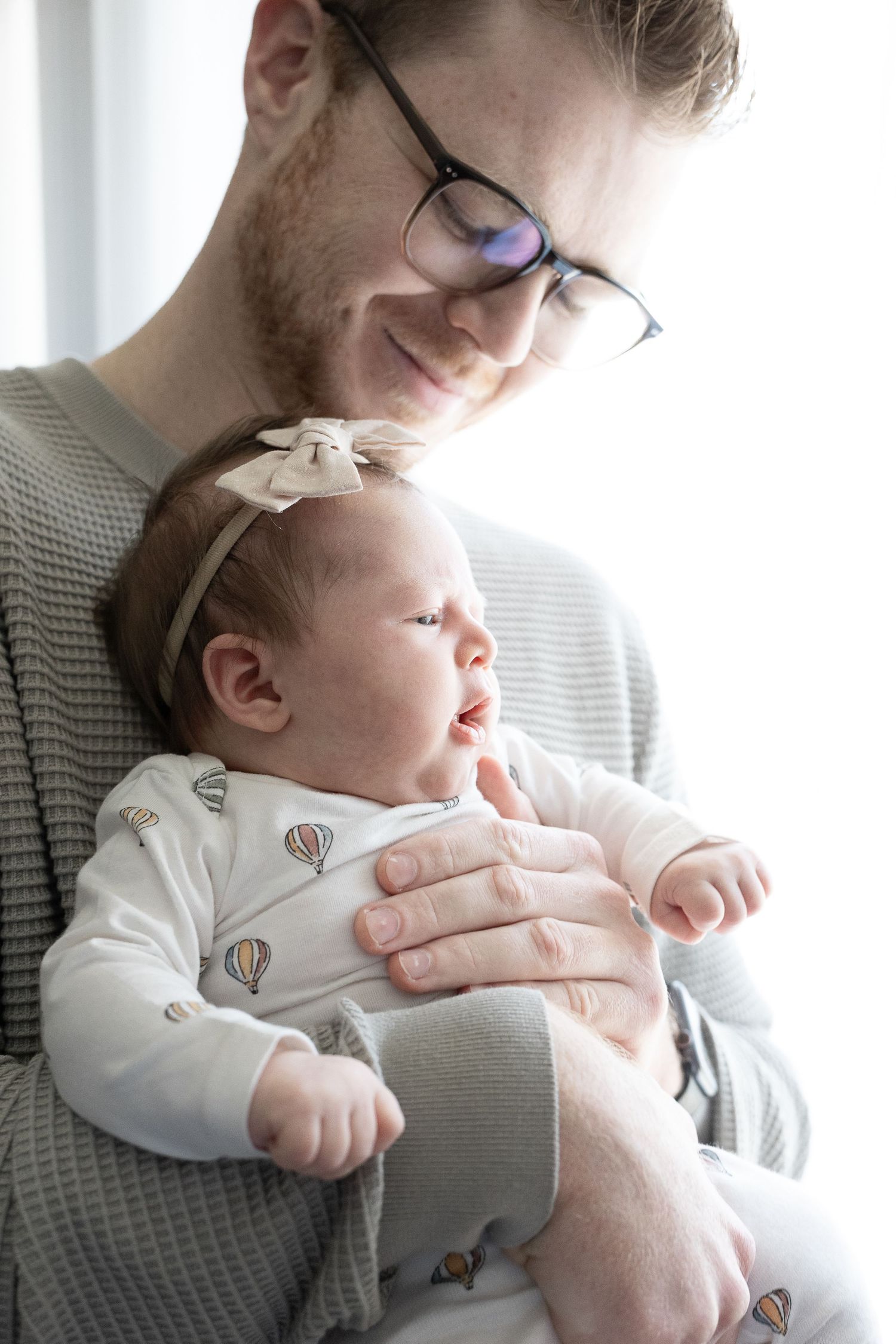 newborn baby is held by her father in photography studio belconnen canberra
