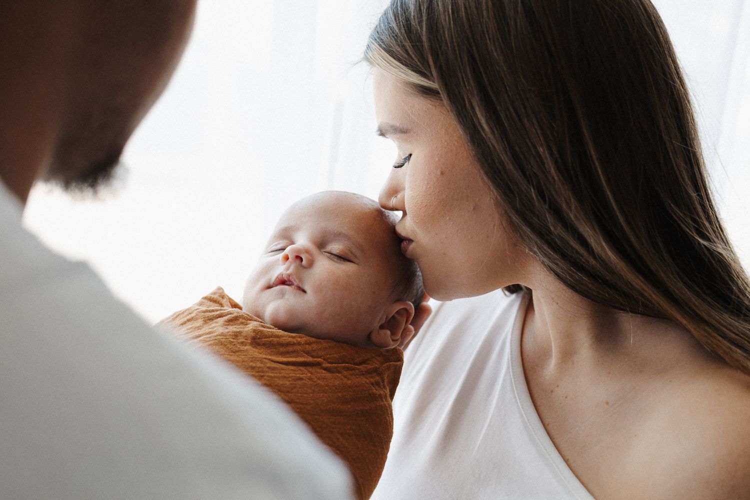 Mother kisses her newborn baby in Belconnen Canberra photographic studio