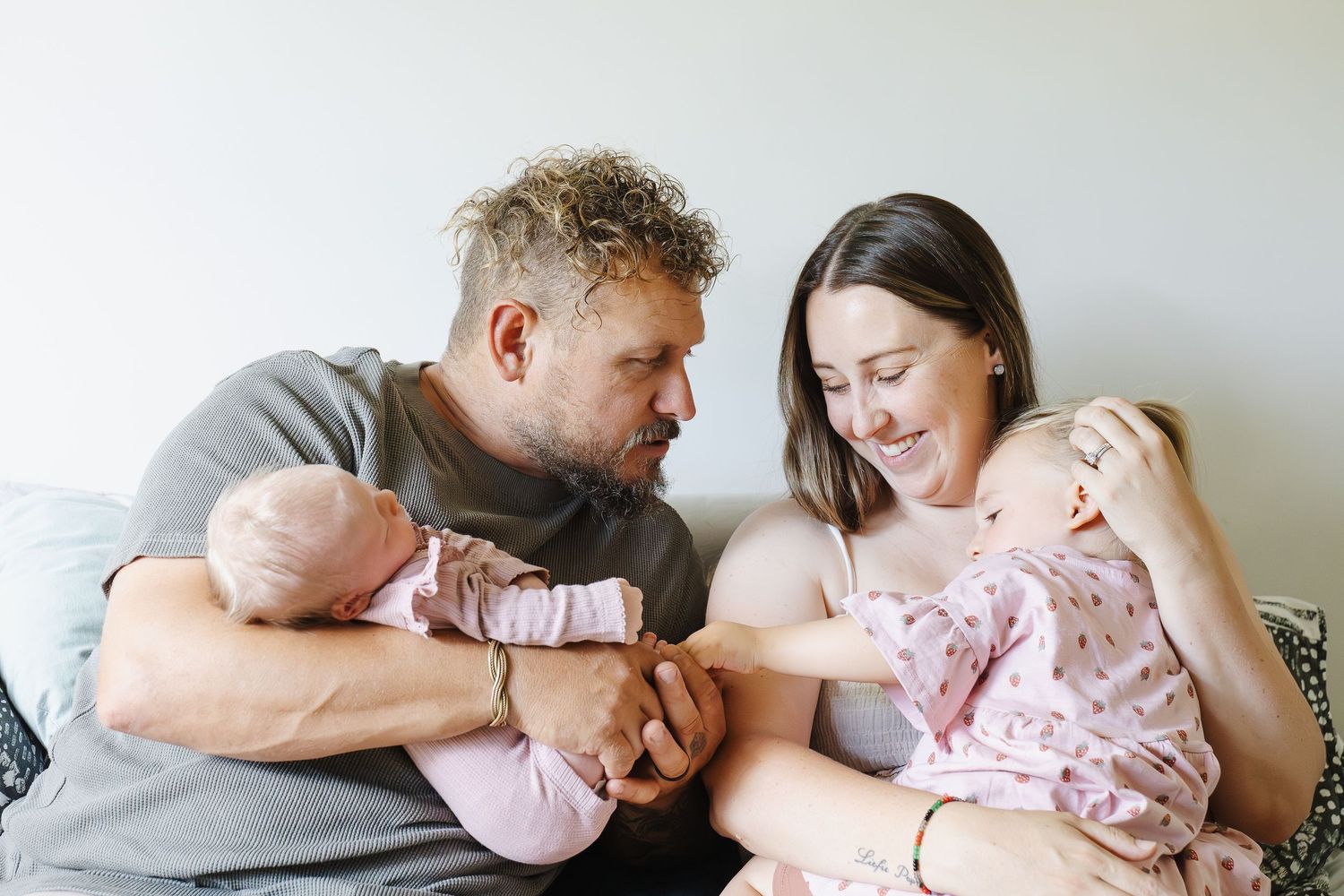 Family of four play on the bed in an in home newborn photoshoot in Canberra