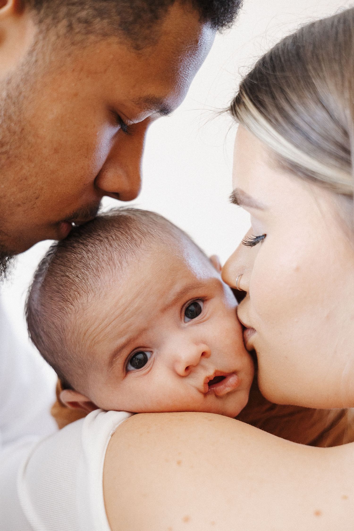 Parents kissing their newborn baby in Belconnen Canberra photography studio