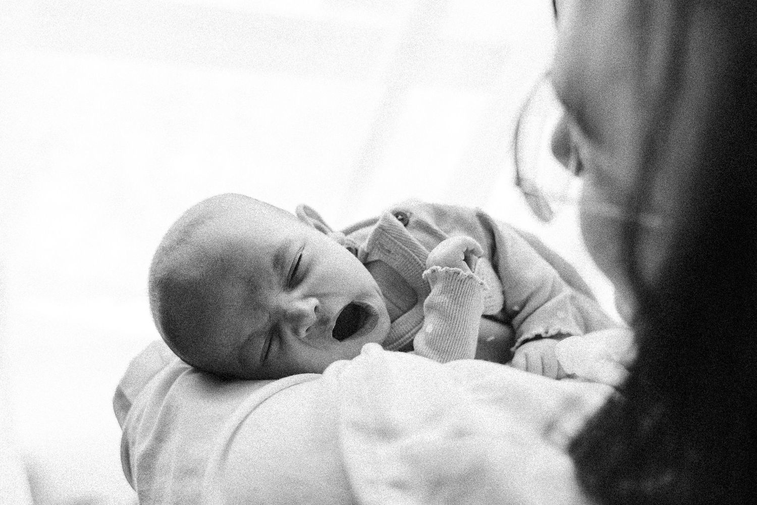 yawning baby cuddled by mum in newborn photography studio canberra