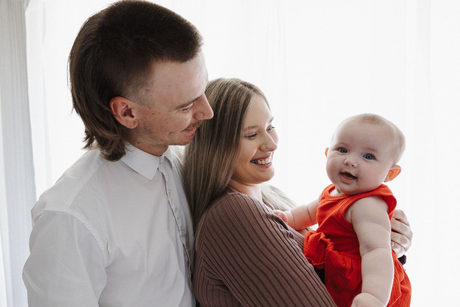Laughing baby girl with her parents in a family photoshoot in Canberra studio