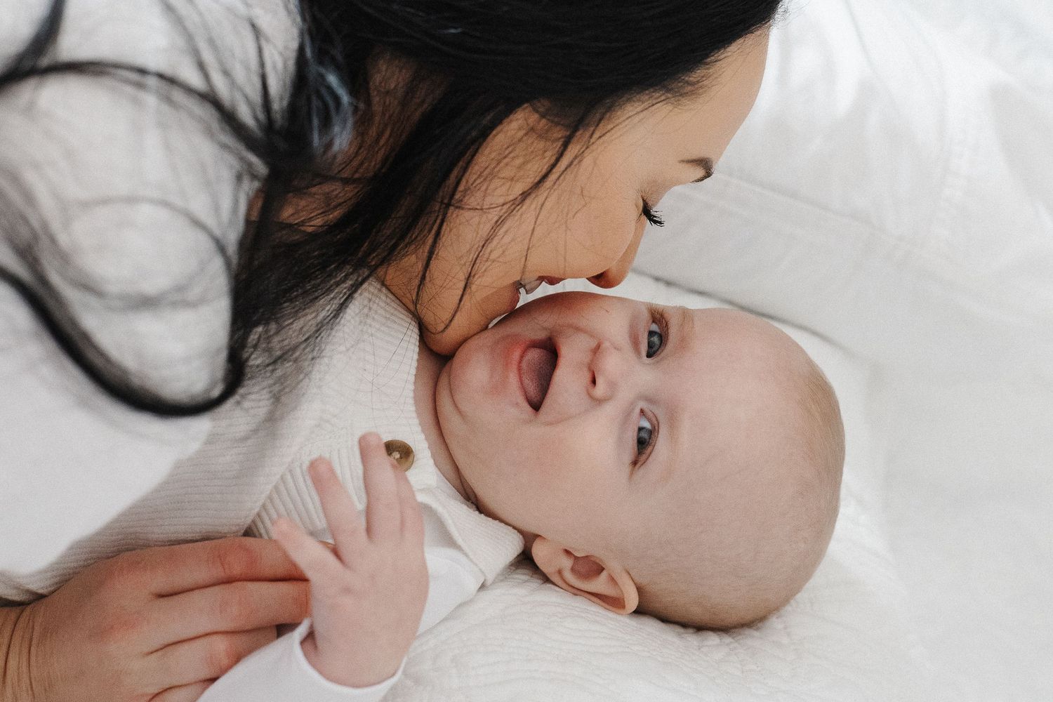 A mother kisses her laughing baby in a Canberra lifestyle in-home family photoshoot