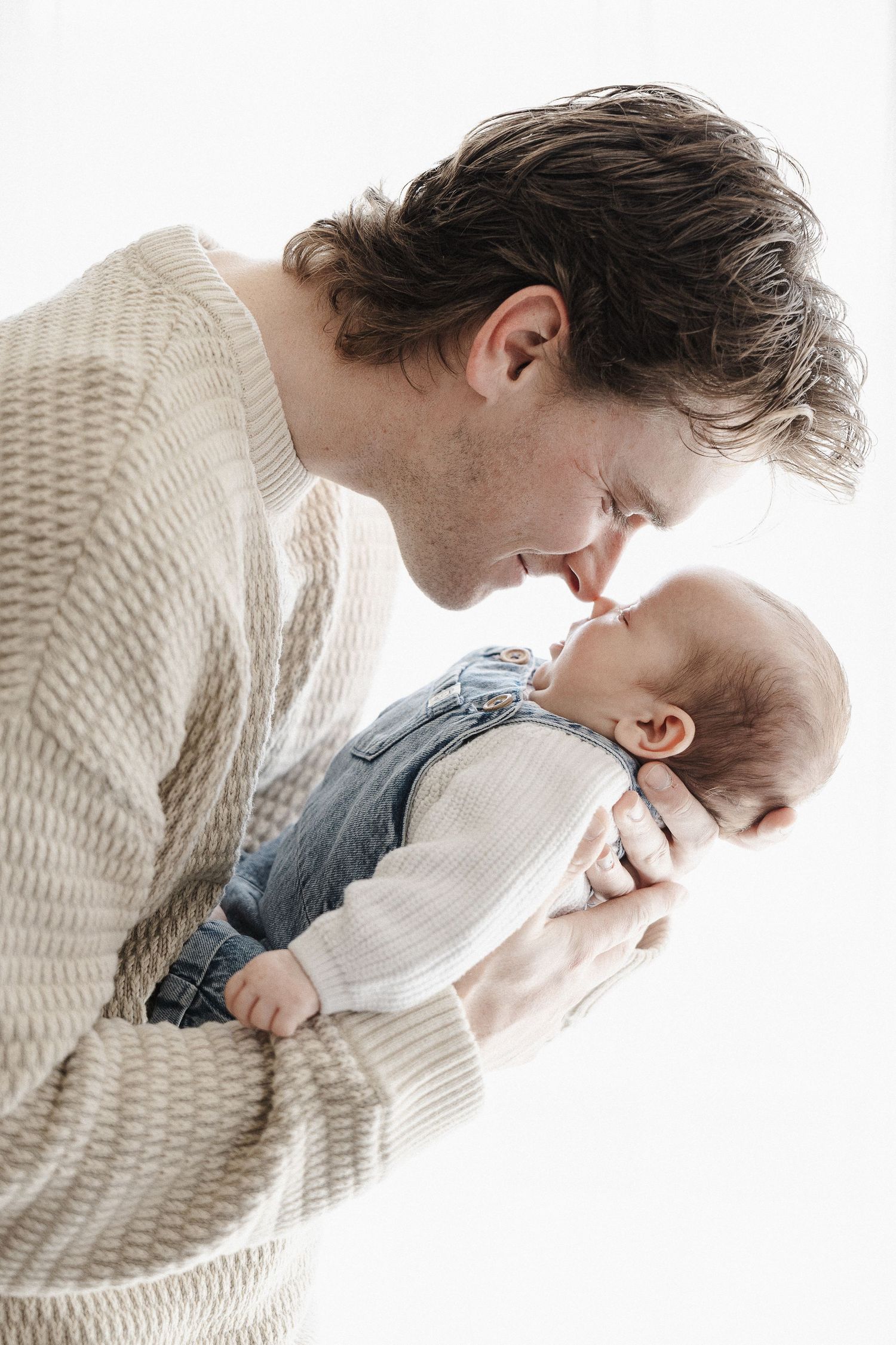 Father touches noses with newborn baby in Belconnen Canberra photography studio