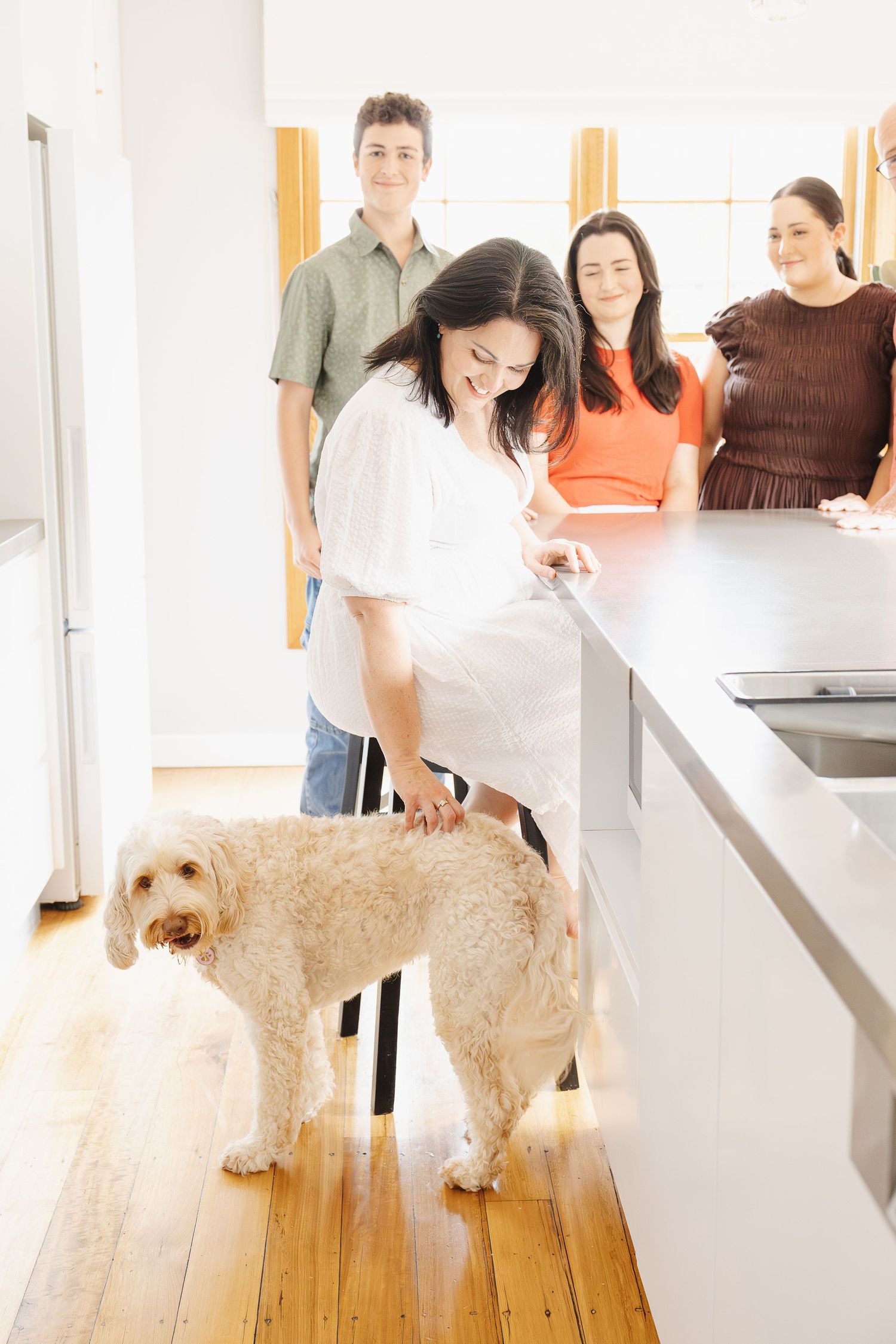 A mum scratches her dog in the kitchen of her Canberra home in a family photoshoot
