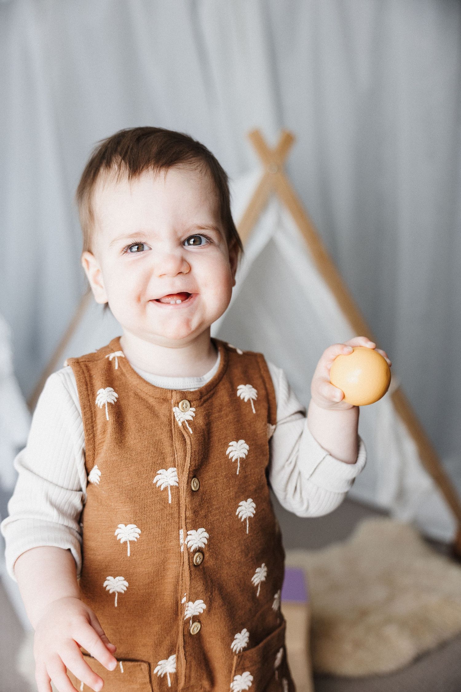 Toddler laughs with a ball in Canberra milestone photography session