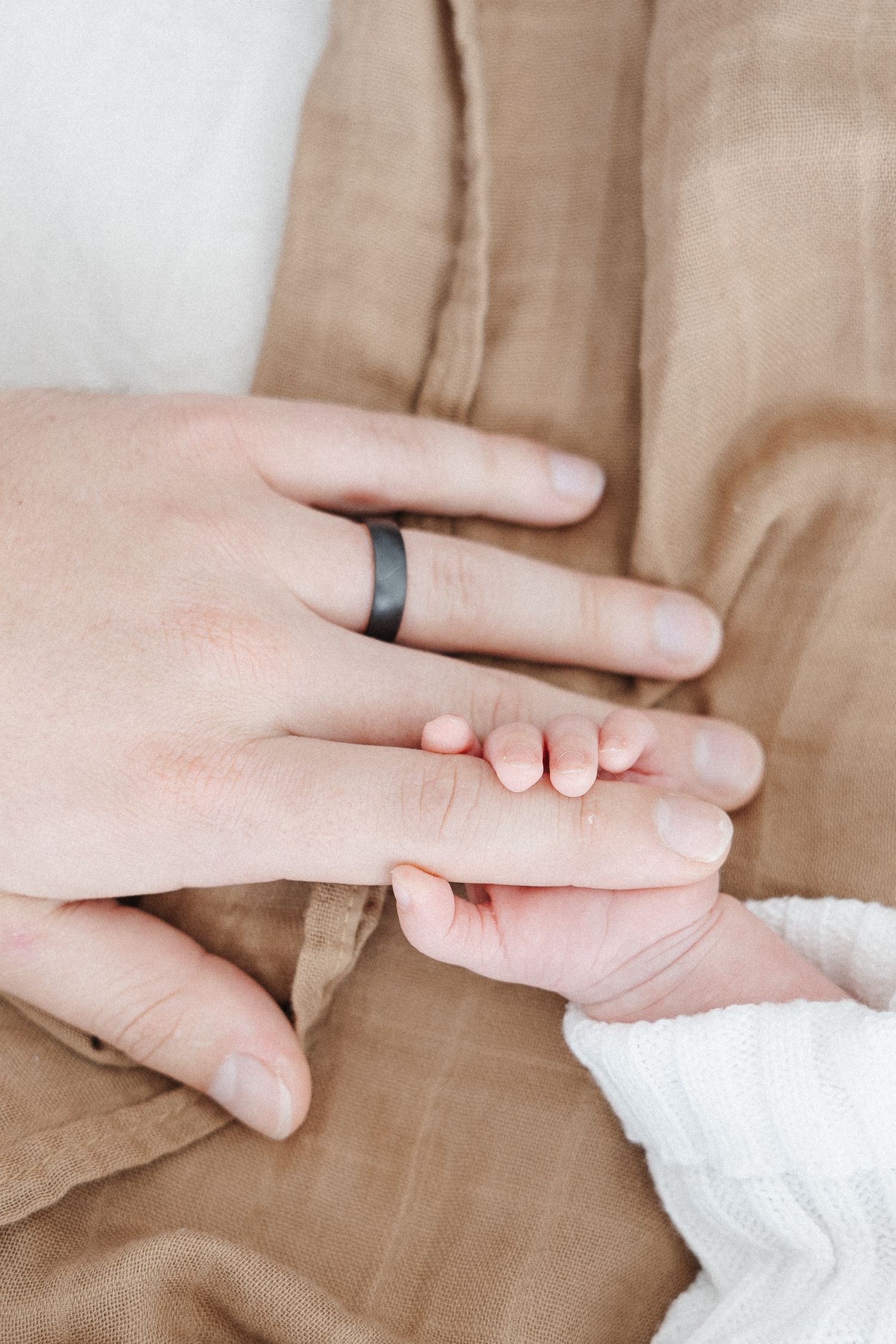 A newborn baby holds his father's hand in Canberra