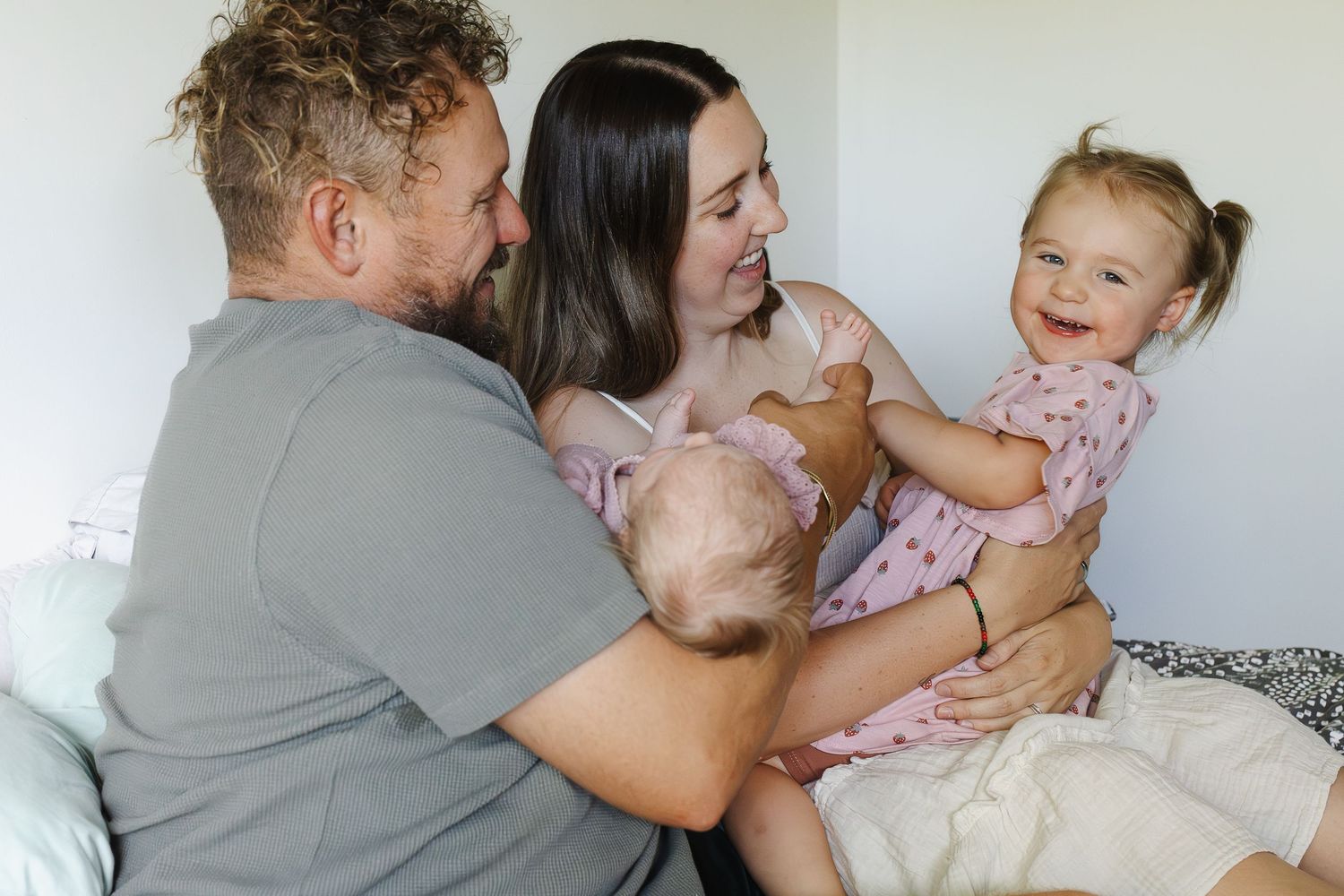 Family plays on the bed in newborn photoshoot Canberra