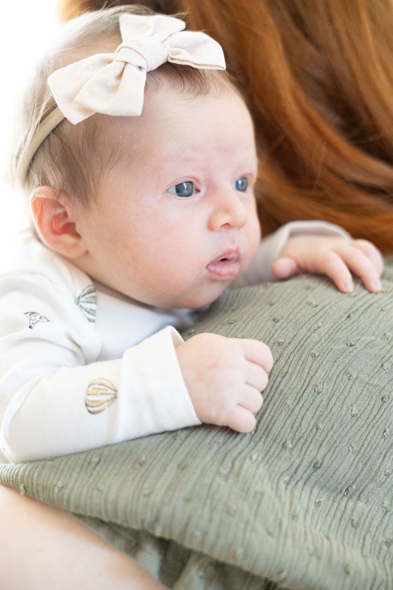 alert newborn looking over mums shoulder in photography studio canberra