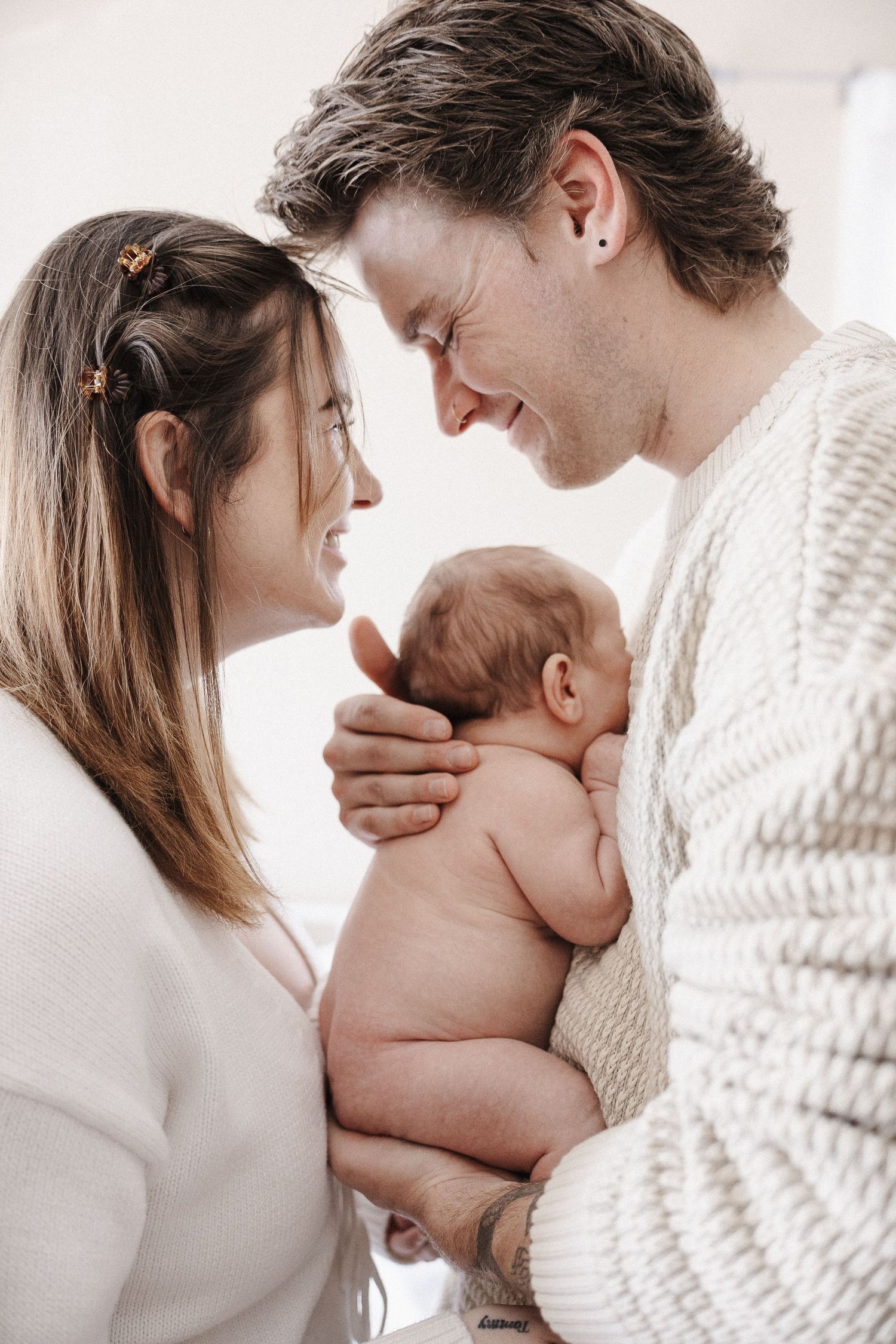 Parents of naked newborn laughing together in Belconnen Canberra photography studio