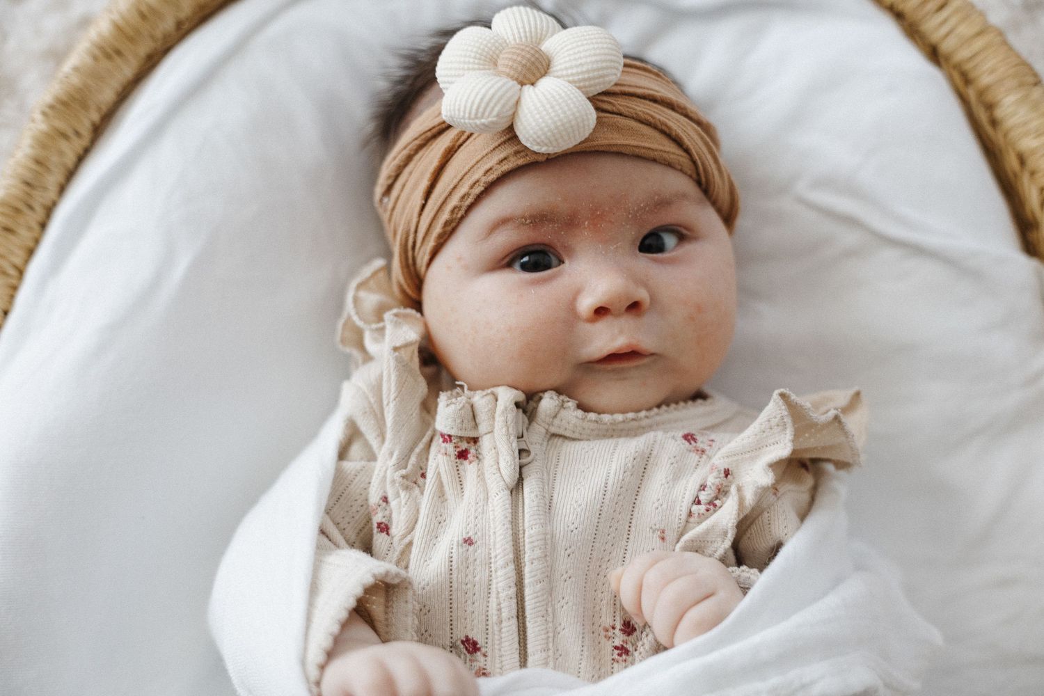 Baby girl with bow looks at the camera in Canberra newborn studio photoshoot