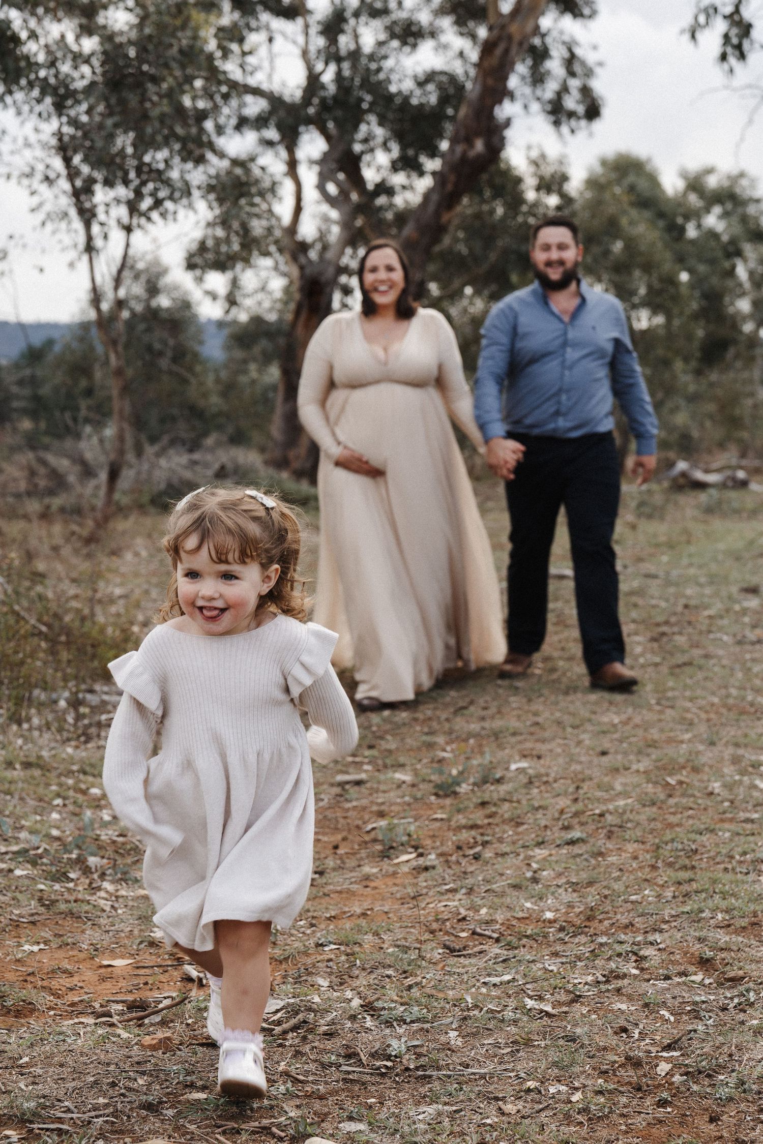 maternity photoshoot in Canberra bushland with little girl running towards camera