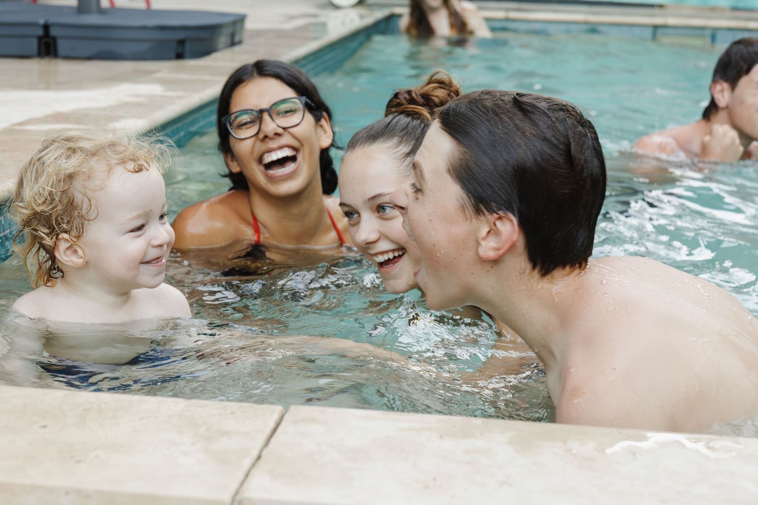 Canberra family with teenagers and a toddler in a lifestyle family photoshoot is photographed while playing in the backyard swimming pool.