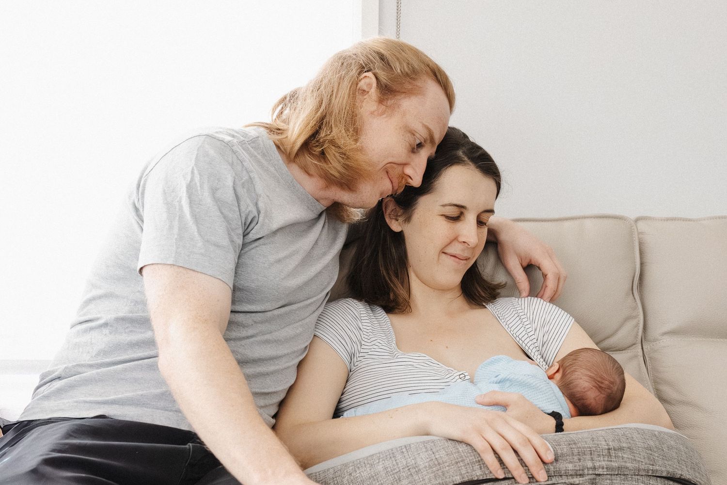 Proud parents gaze at their newborn baby breastfeeding in Canberra photoshoot