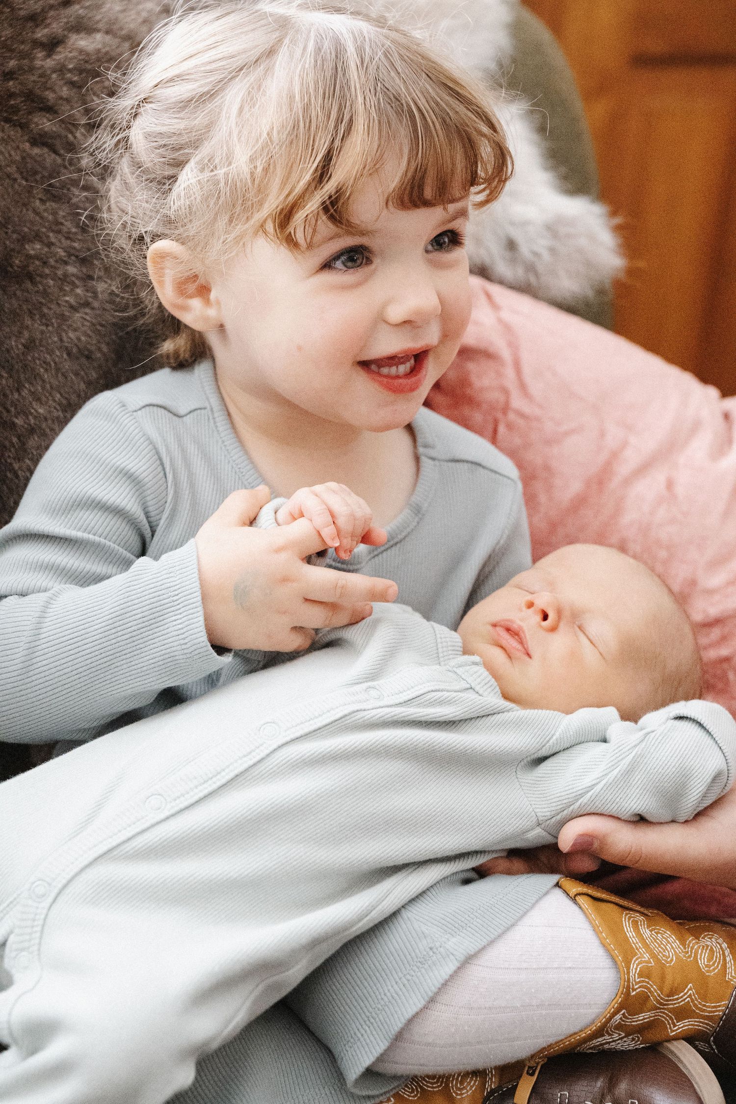 A toddler big sister proudly holds her baby brother in a newborn photoshoot in Canberra