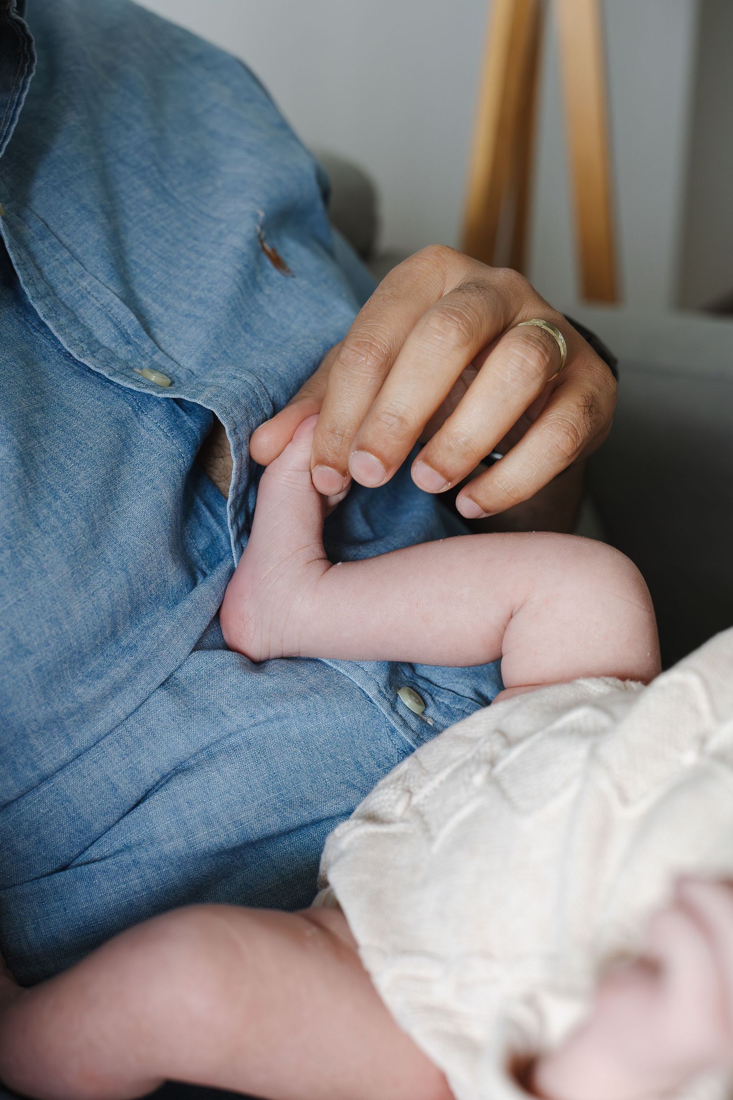 dad plays with tiny baby's toes in newborn photoshoot