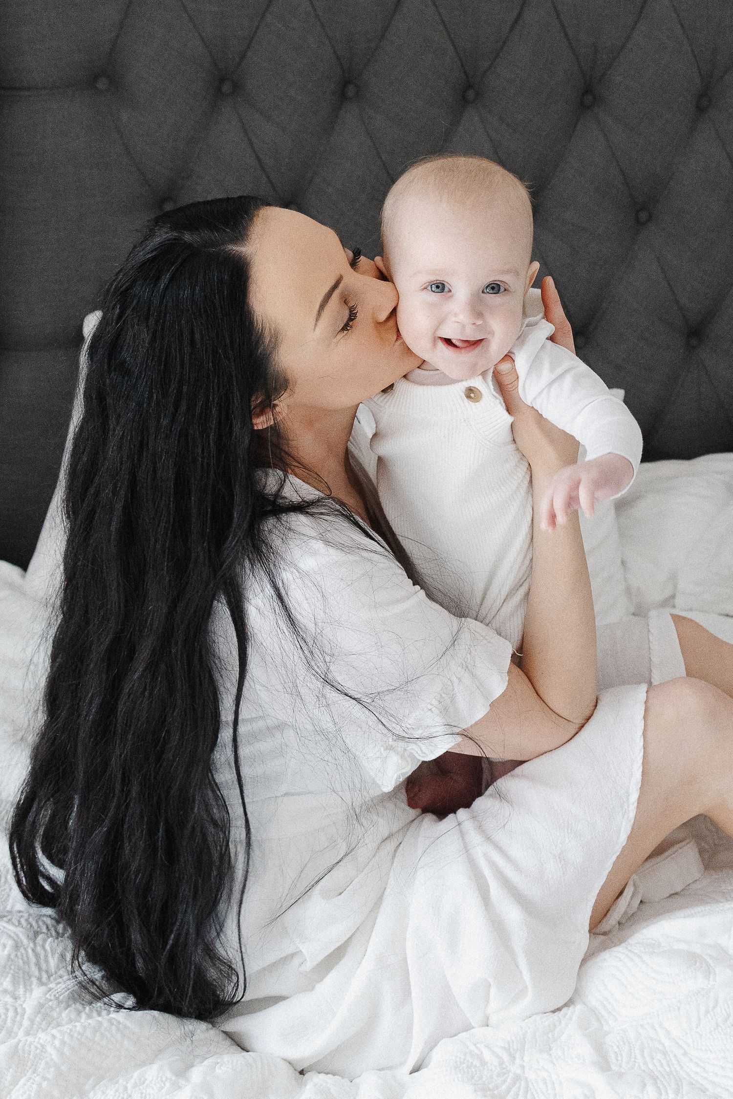 Mum kisses baby in bed in Canberra family photoshoot