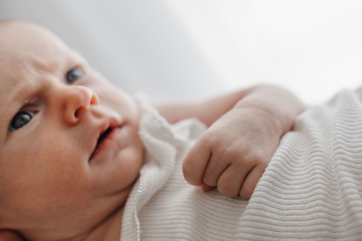 A baby frowns at his dad in a newborrn baby photoshoot in Canberra photo studio